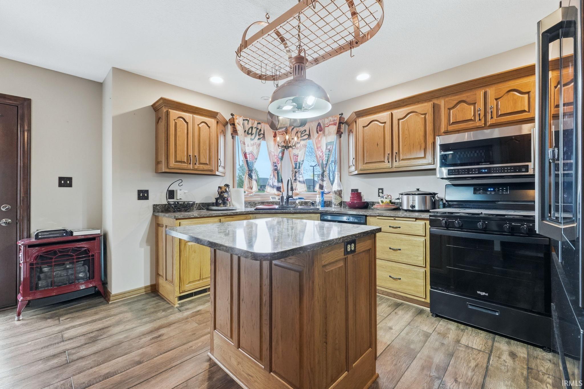 Kitchen featuring gas range, stainless steel microwave, light wood-type flooring, high quality fridge, and wood finish cabinets