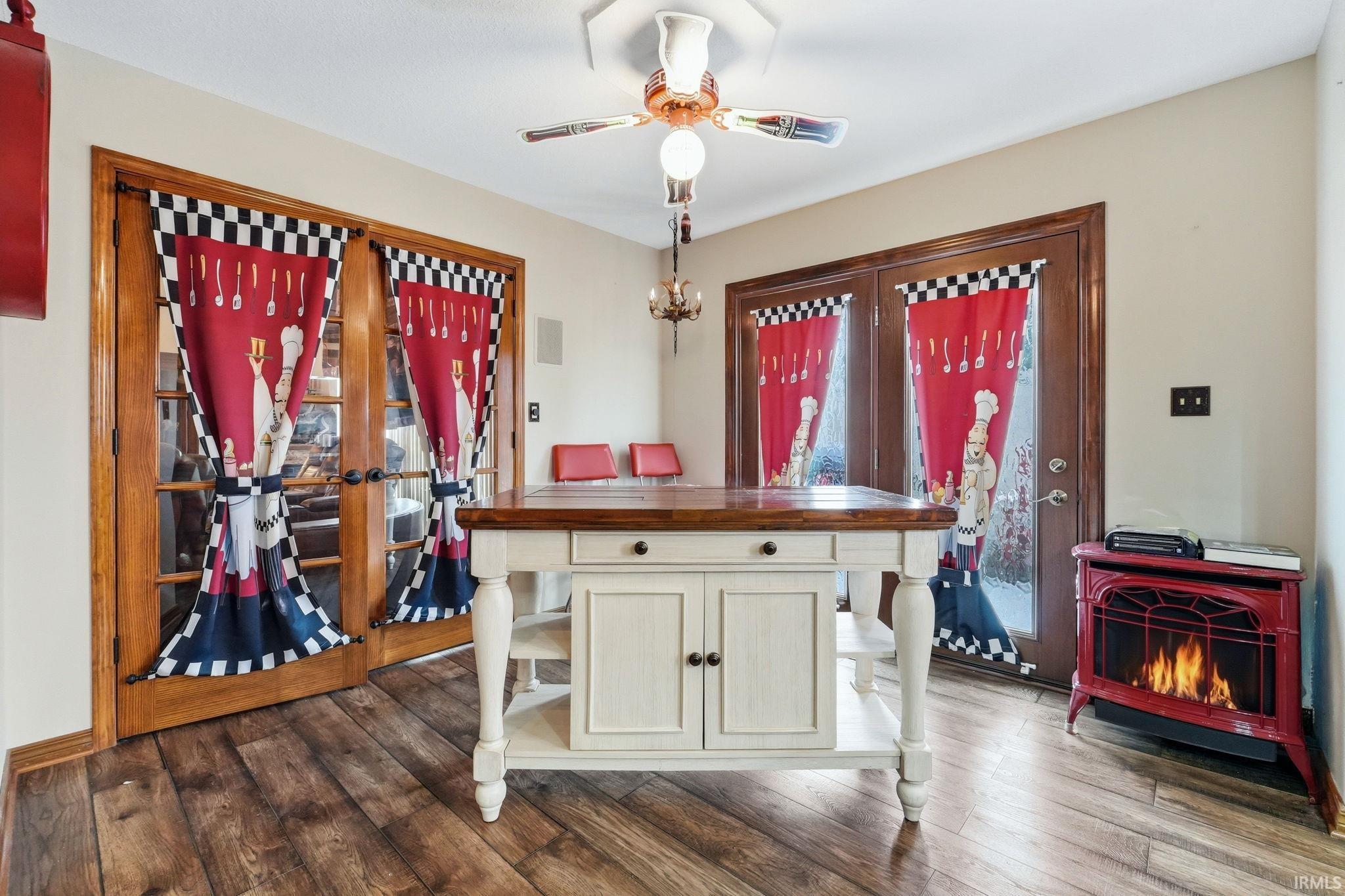 Dining area with dark wood-type flooring, a ceiling fan, and french doors