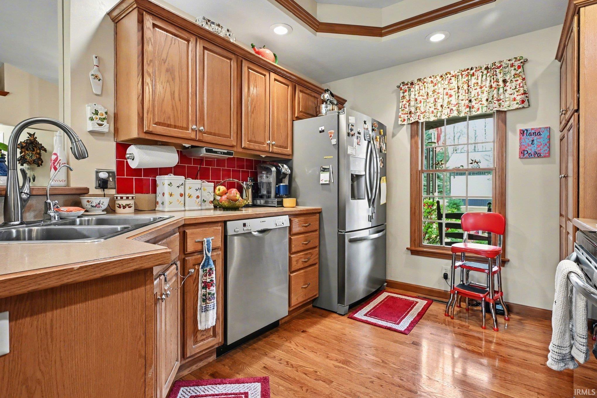 Kitchen with wood finish cabinets, stainless steel appliances, light countertops, light wood-style floors, and recessed lighting
