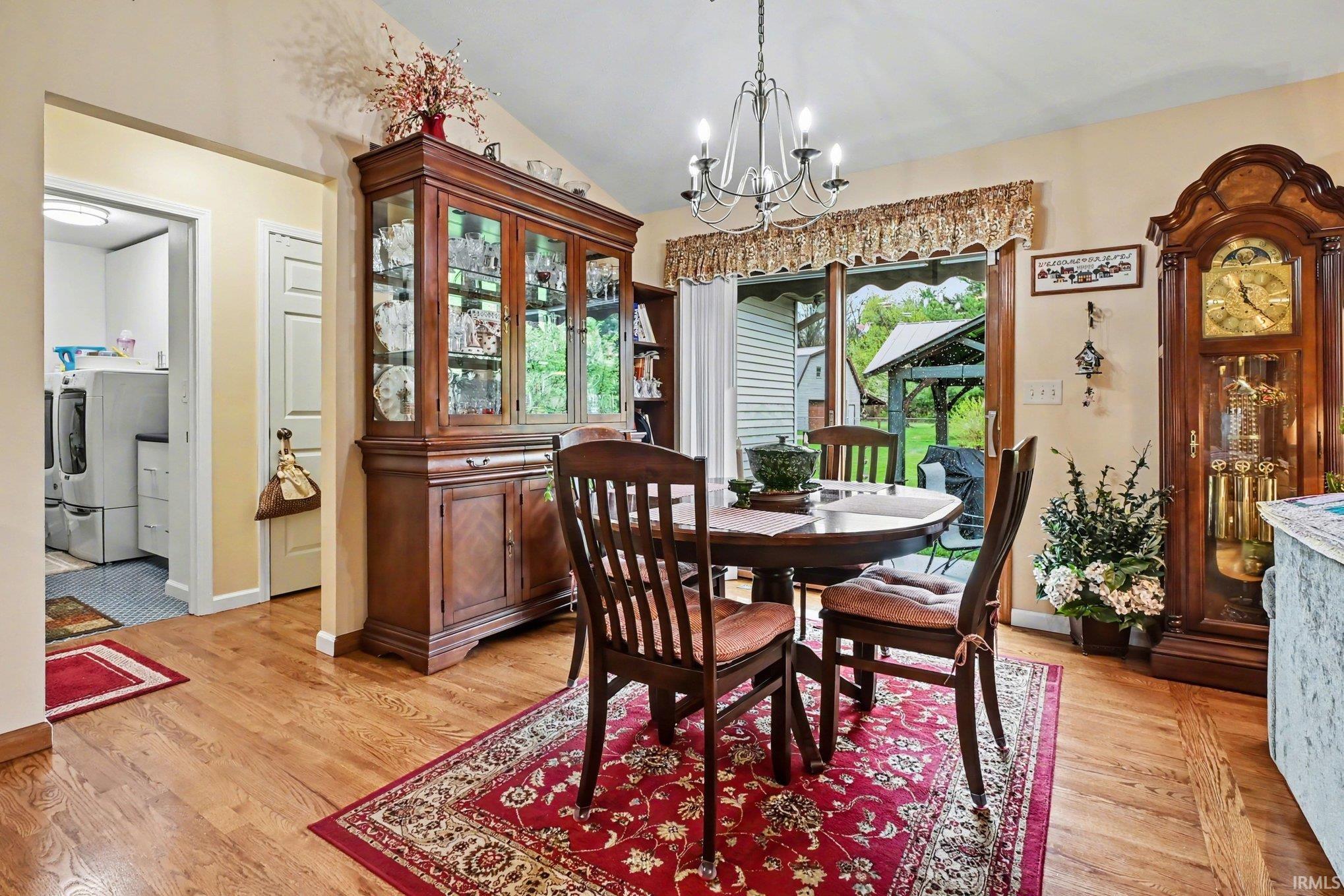 Dining area with lofted ceiling, light wood finished floors, and suspended lighting