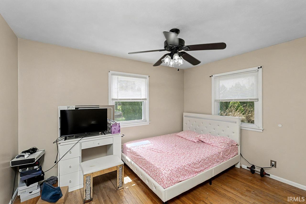 Bedroom featuring multiple windows, hardwood / wood-style flooring, and a ceiling fan