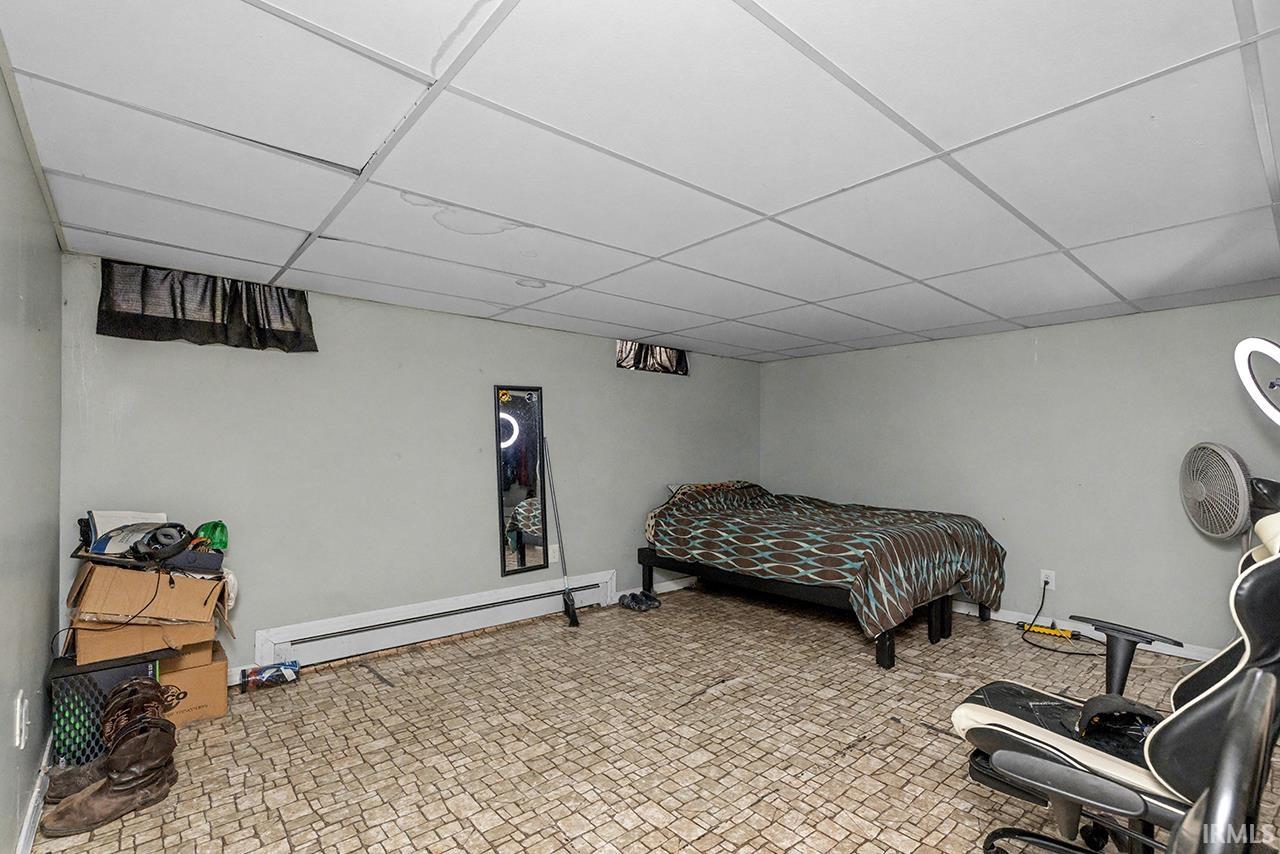 Bedroom with a paneled ceiling and a baseboard heating unit