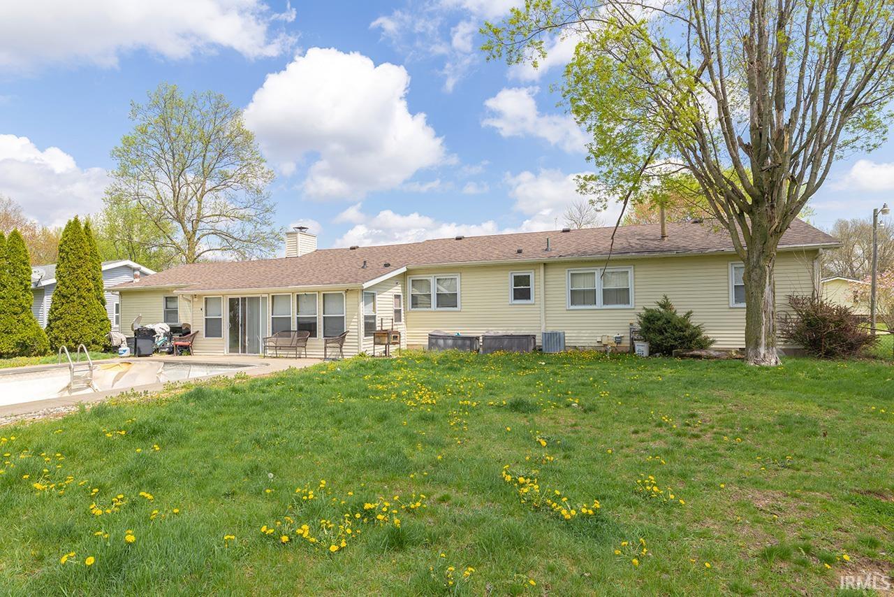 Rear view of property with a patio, a chimney, and a lawn