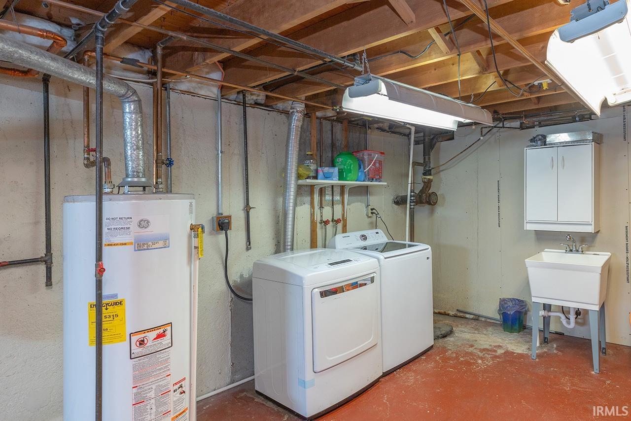 Laundry area featuring gas water heater, concrete flooring, and washer and dryer