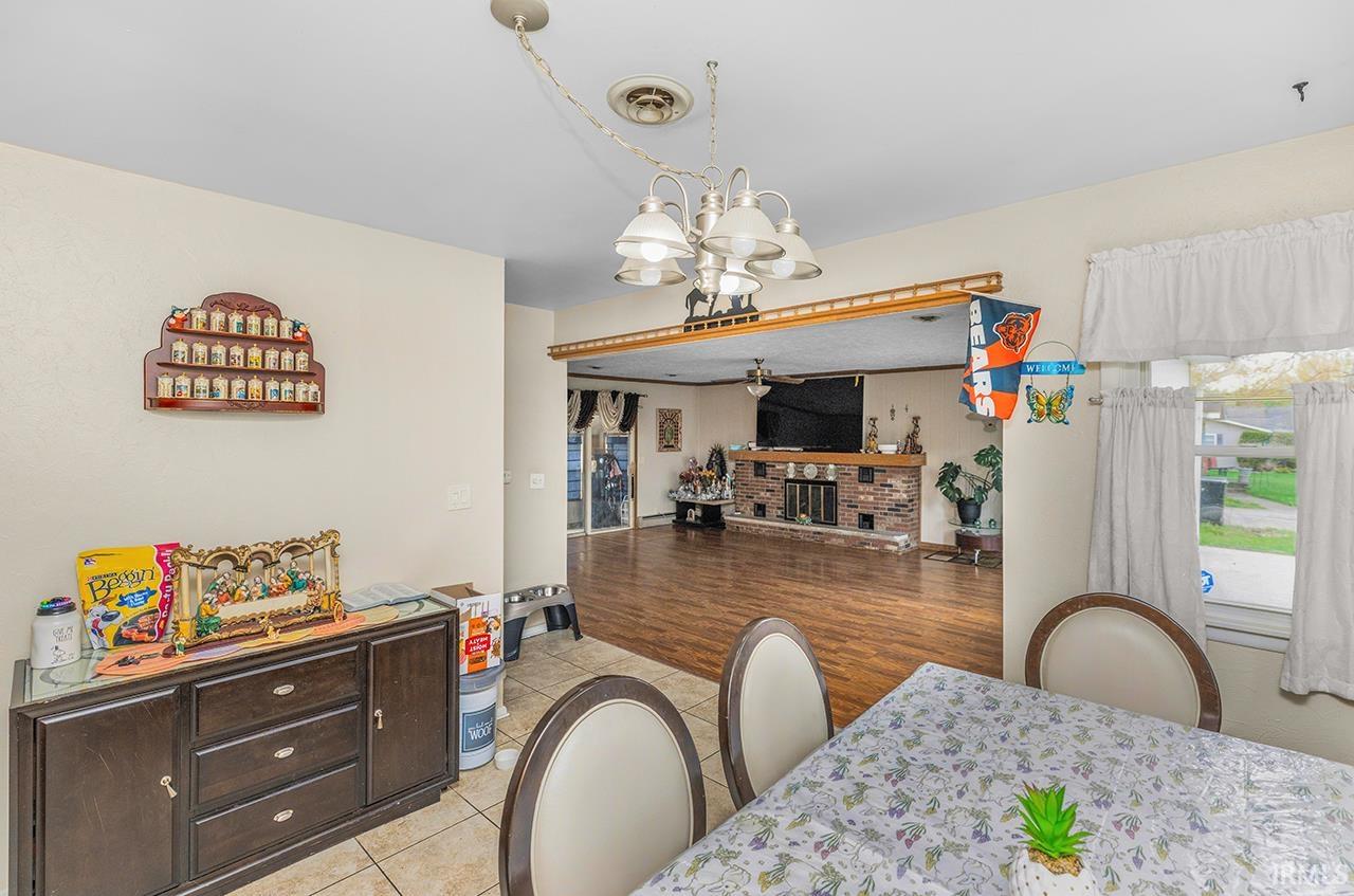 Dining space featuring suspended lighting, light tile patterned flooring, ceiling fan, and a fireplace