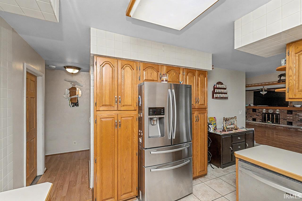 Kitchen featuring stainless steel appliances, decorative backsplash, wood finish cabinets, and light countertops