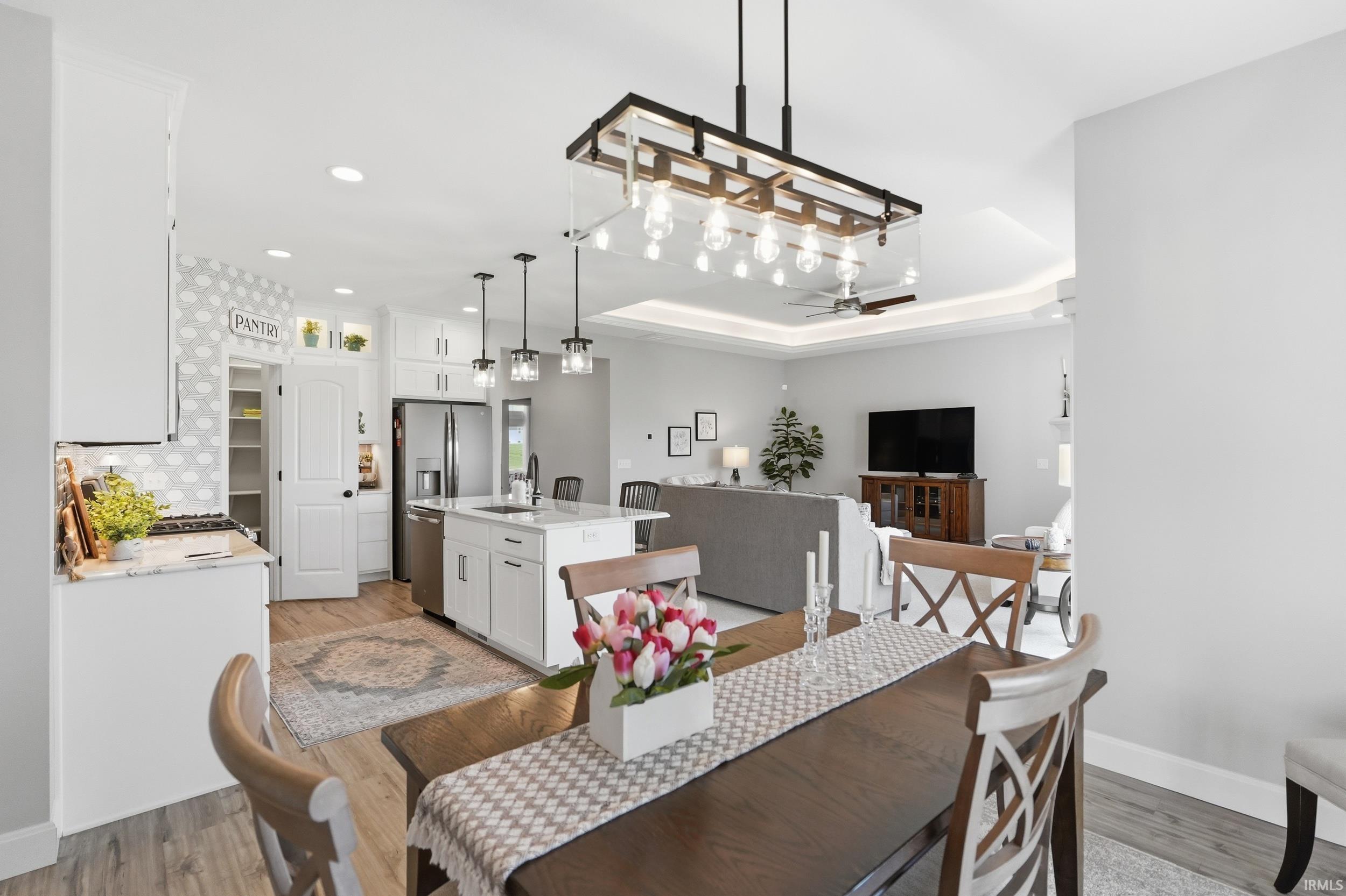 Dining area with light wood finished floors, ceiling fan, a tray ceiling, and recessed lighting