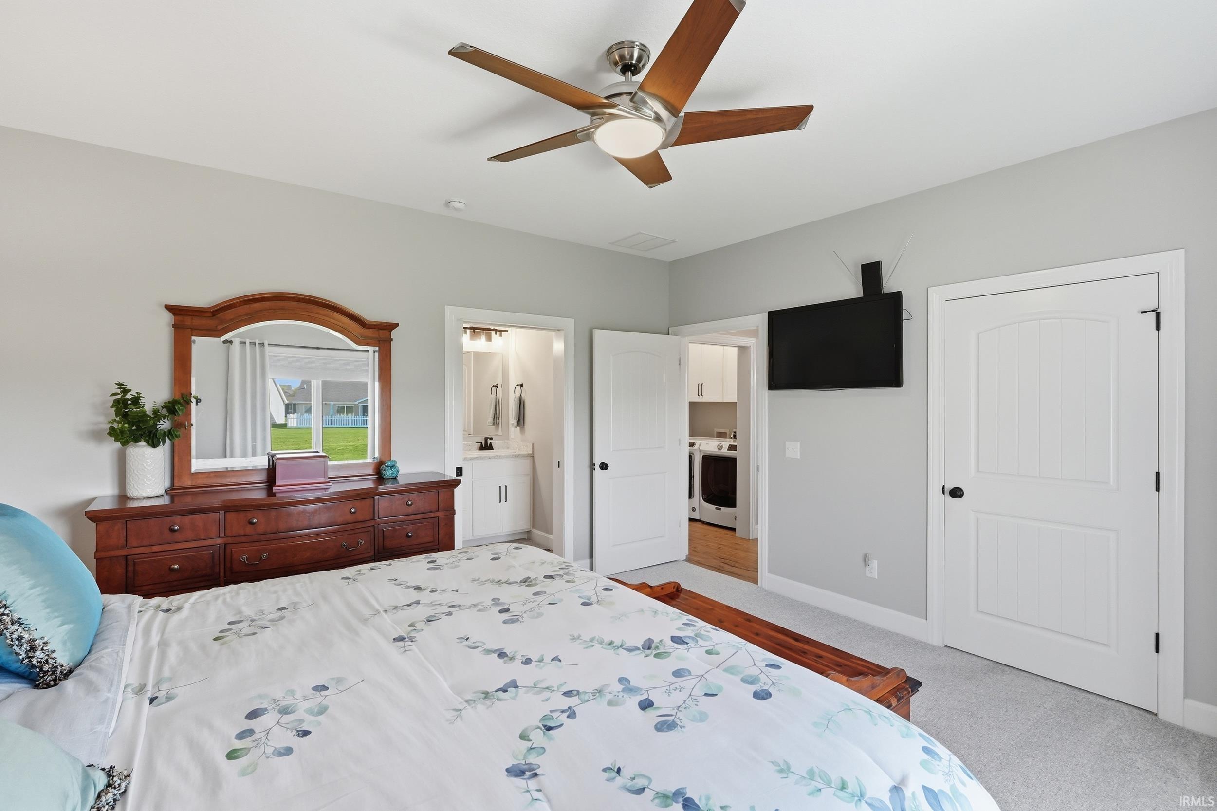 Bedroom with light colored carpet, ensuite bath, and ceiling fan
