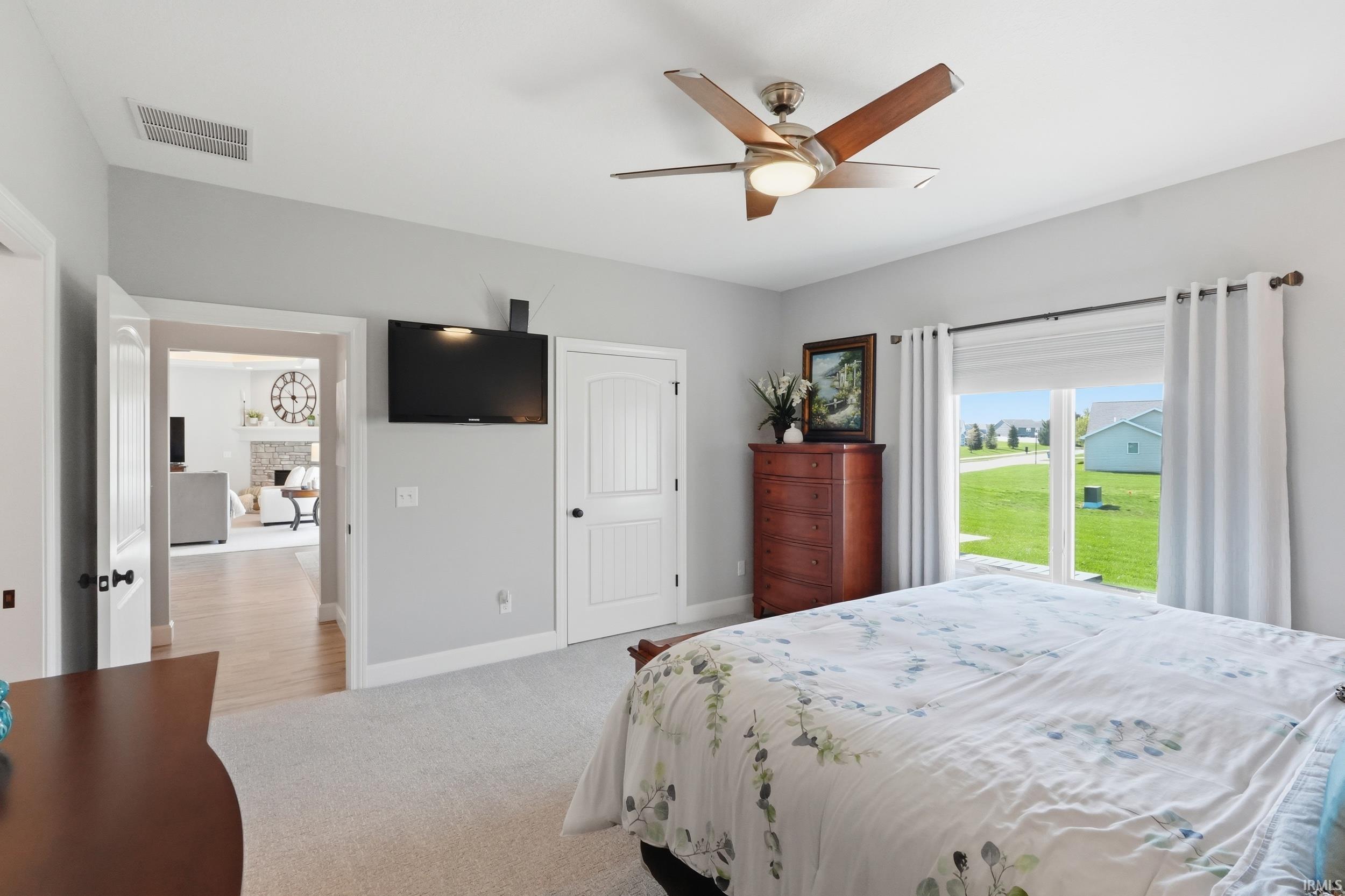 Bedroom featuring light carpet, a ceiling fan, a fireplace, and a closet