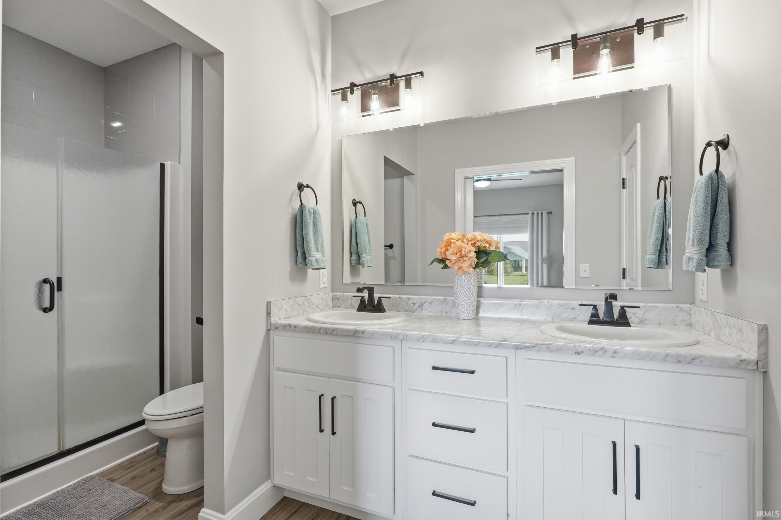 Bathroom with double vanity, a stall shower, and light wood finished floors