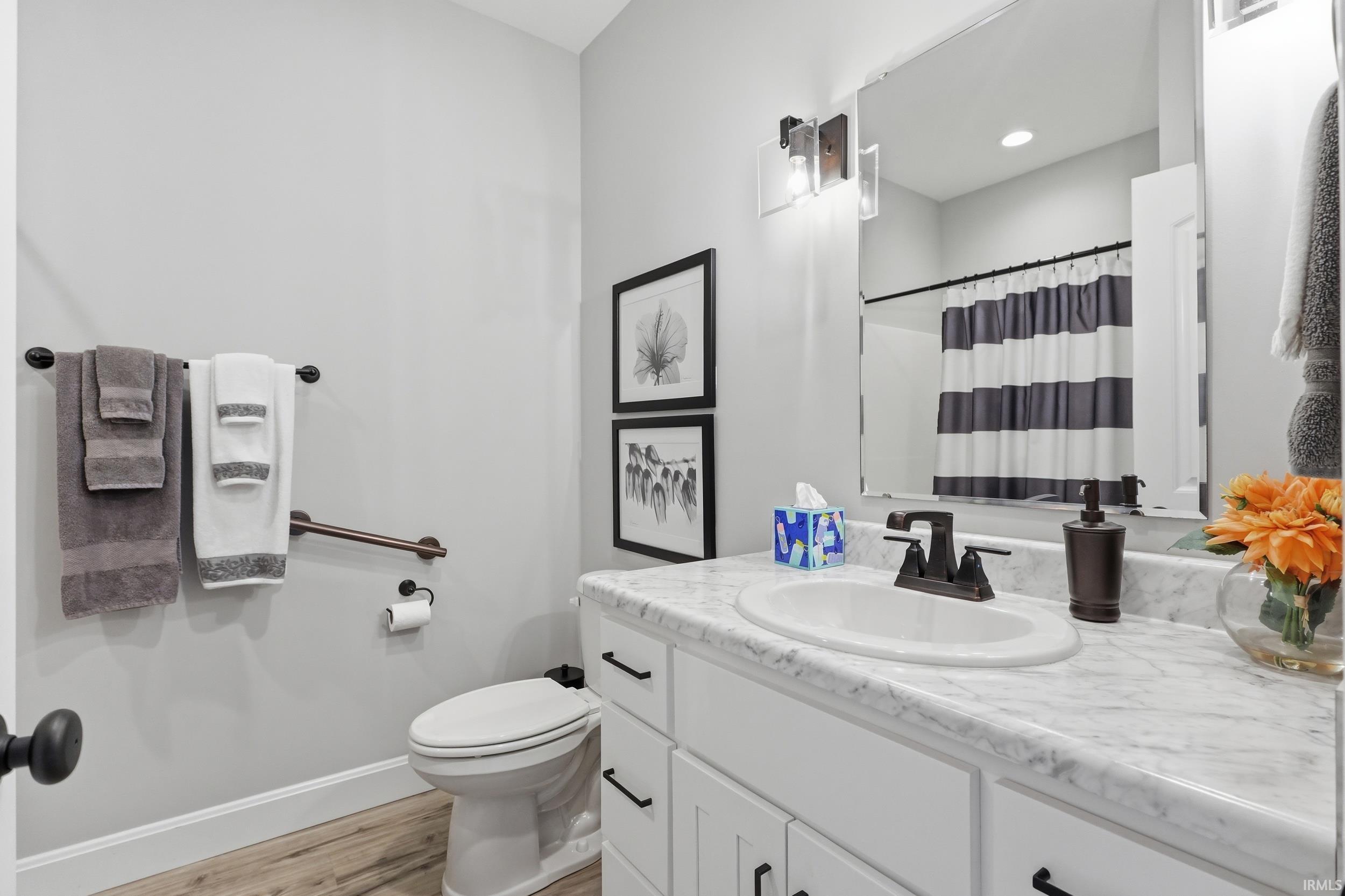 Full bathroom with vanity, curtained shower, and light wood-type flooring