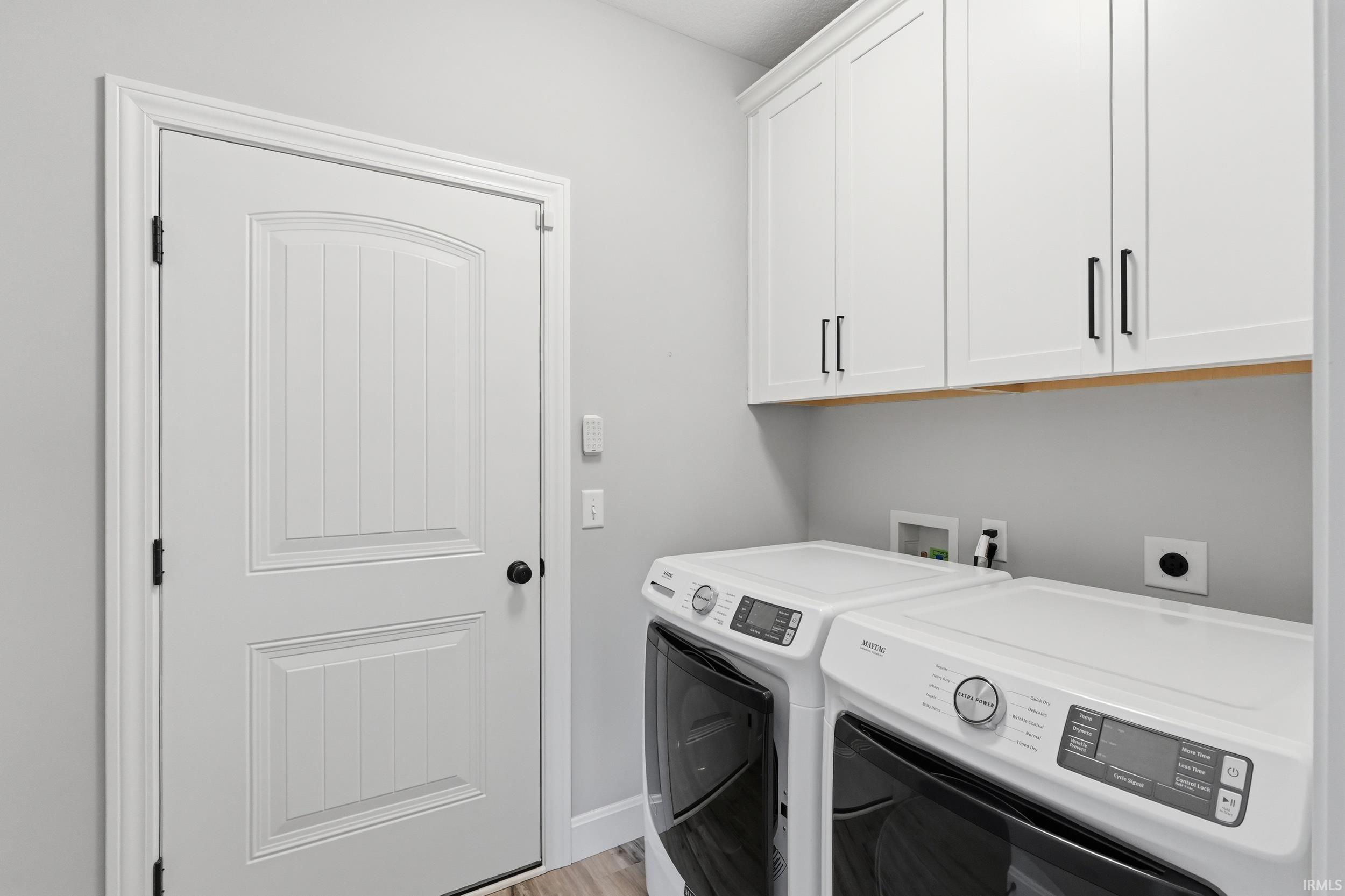 Laundry room featuring cabinet space, washer and clothes dryer, and light wood-type flooring
