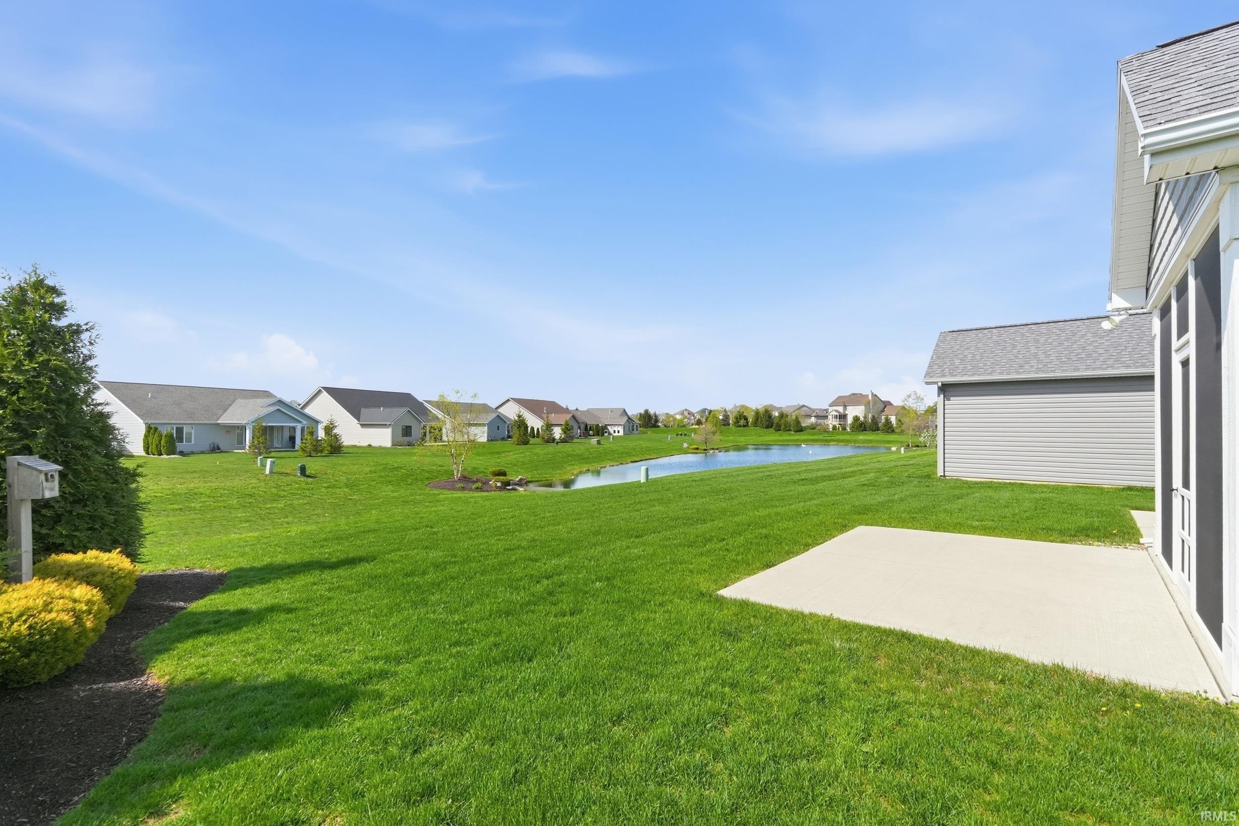 View of grassy yard with a water view, a patio, and a residential view