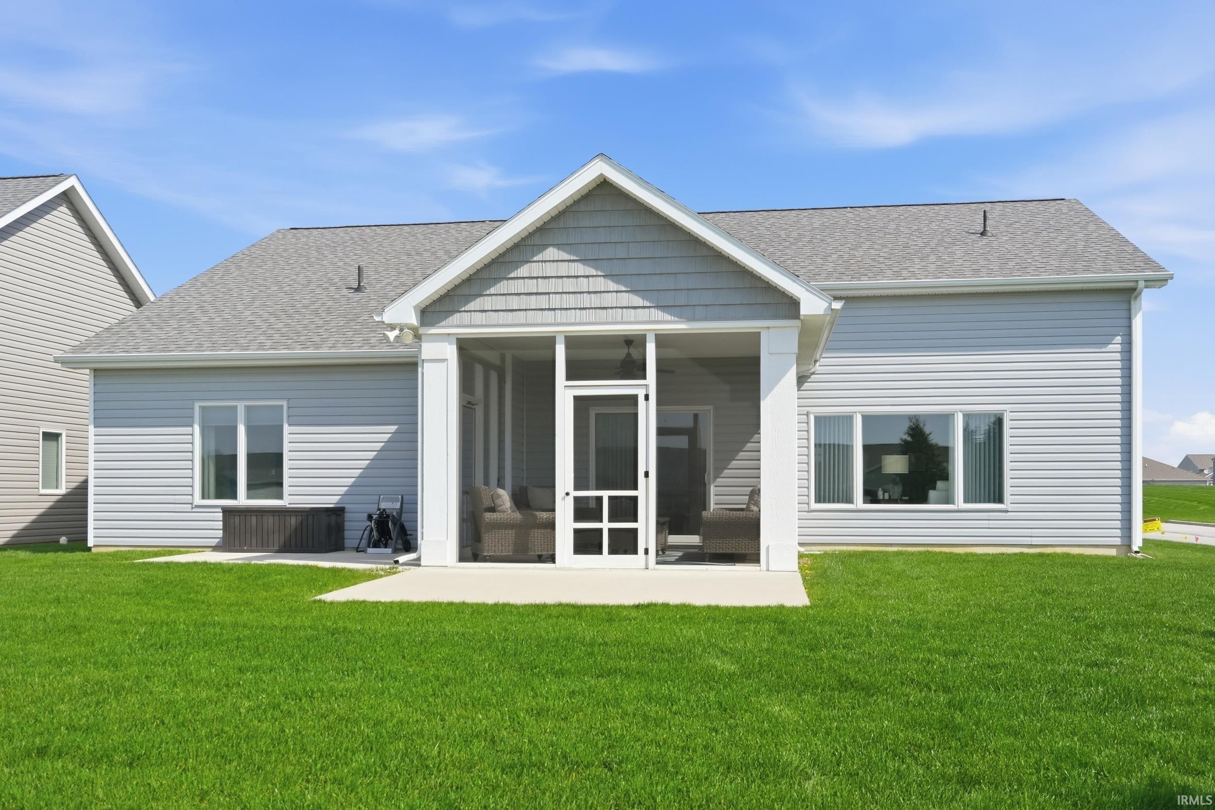 Back of house with a yard, a patio area, and roof with shingles