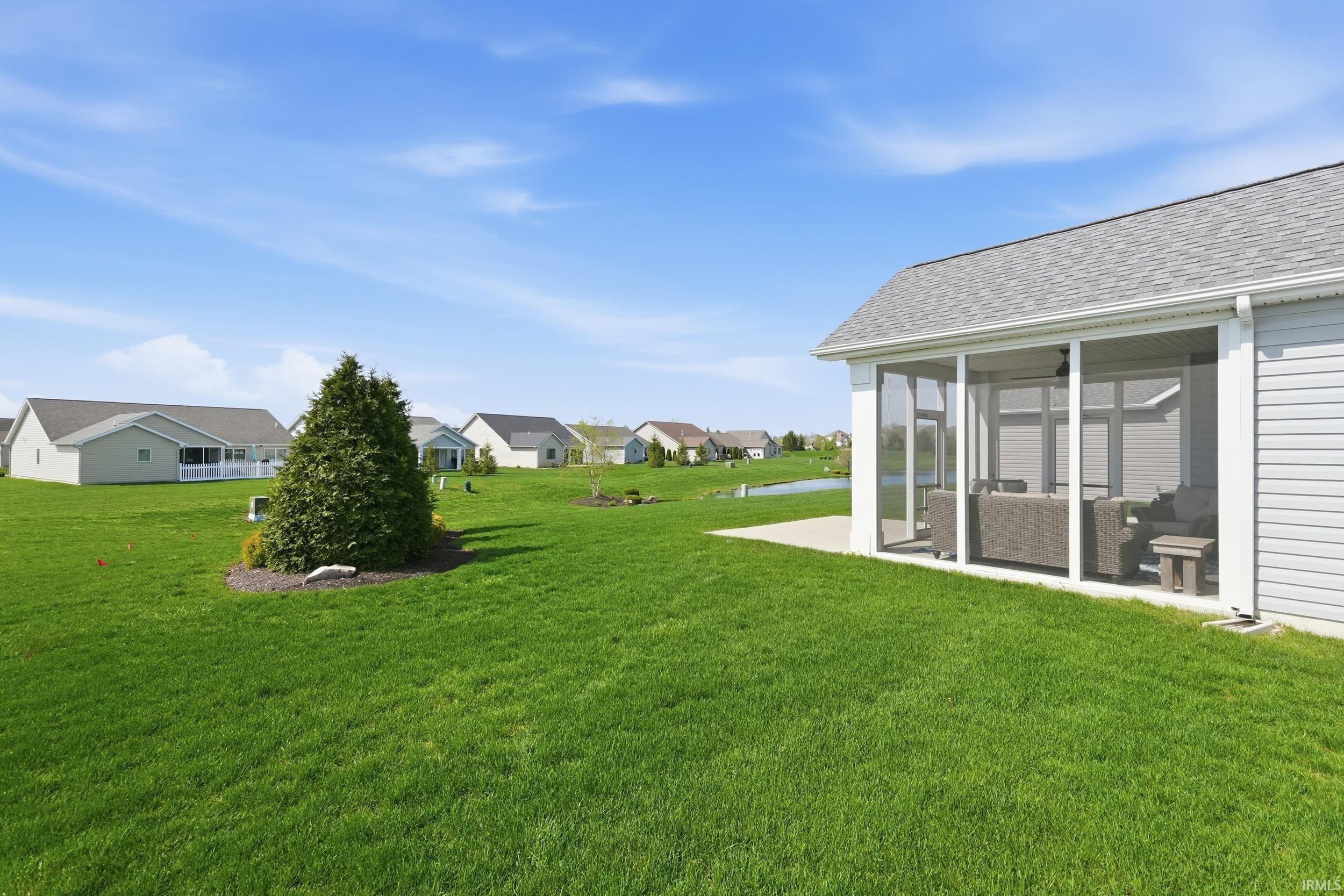 View of grassy yard featuring a sunroom and a residential view