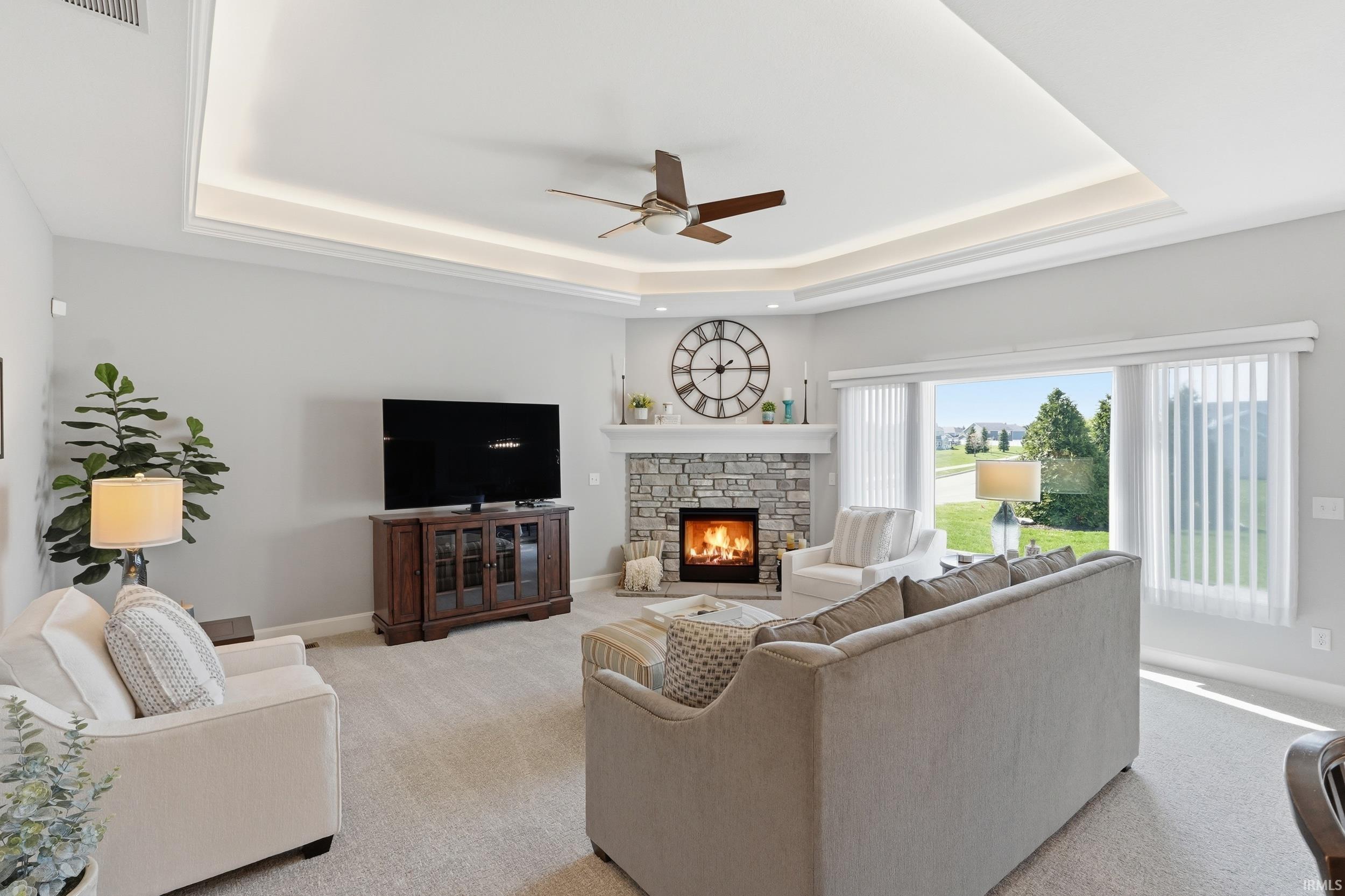 Carpeted living area featuring a ceiling fan and a fireplace