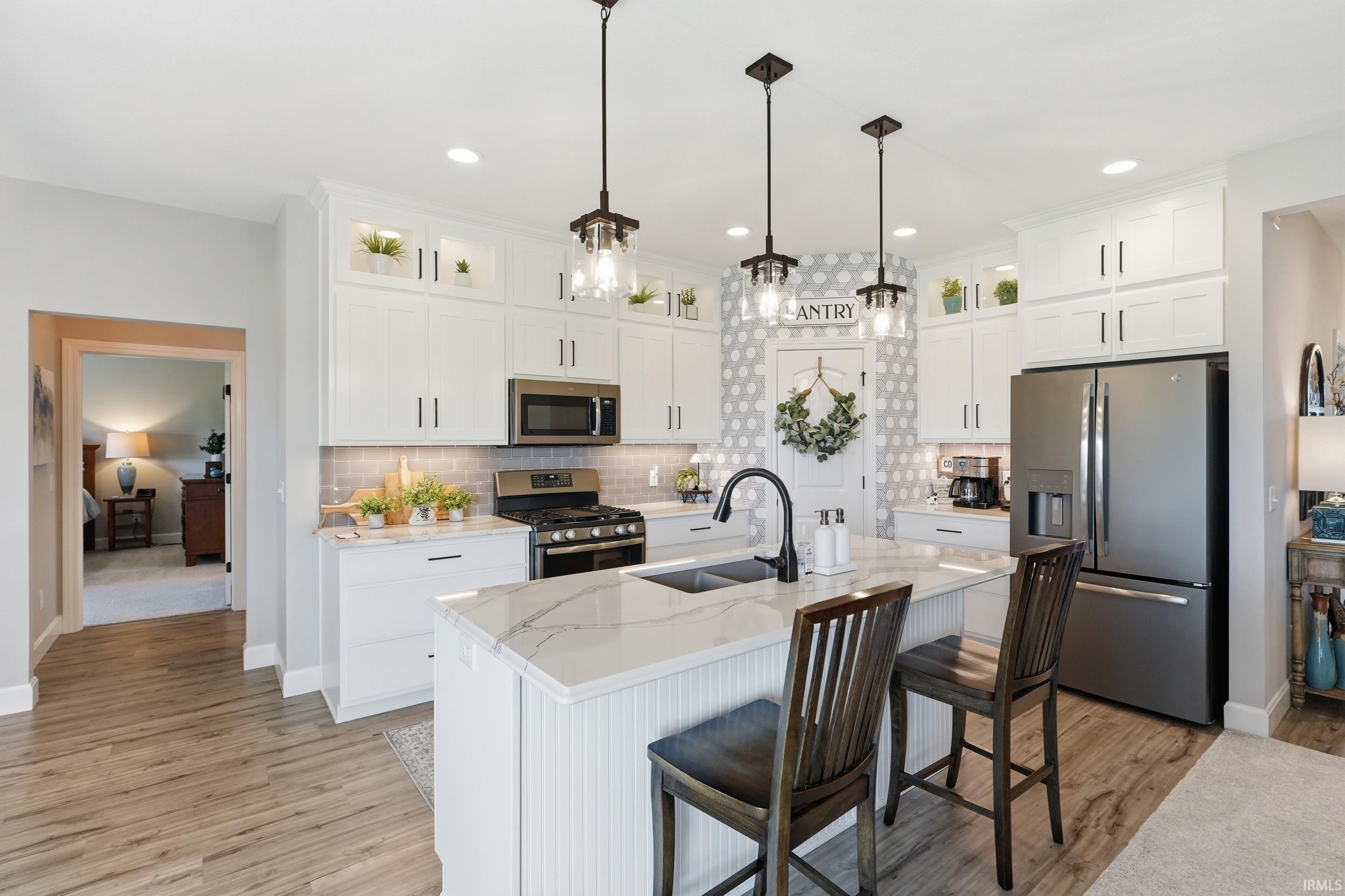 Kitchen featuring glass fronted cabinets, stainless steel appliances, white cabinets, a kitchen breakfast bar, and light stone countertops