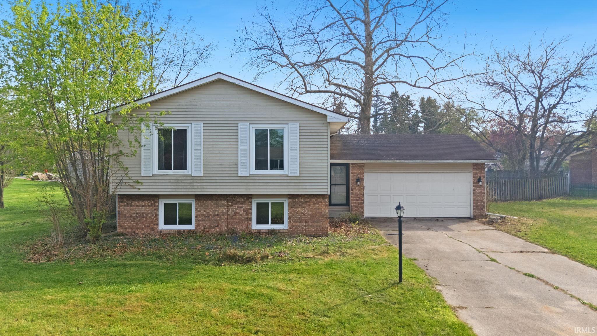 Split level home featuring brick siding, a garage, and driveway
