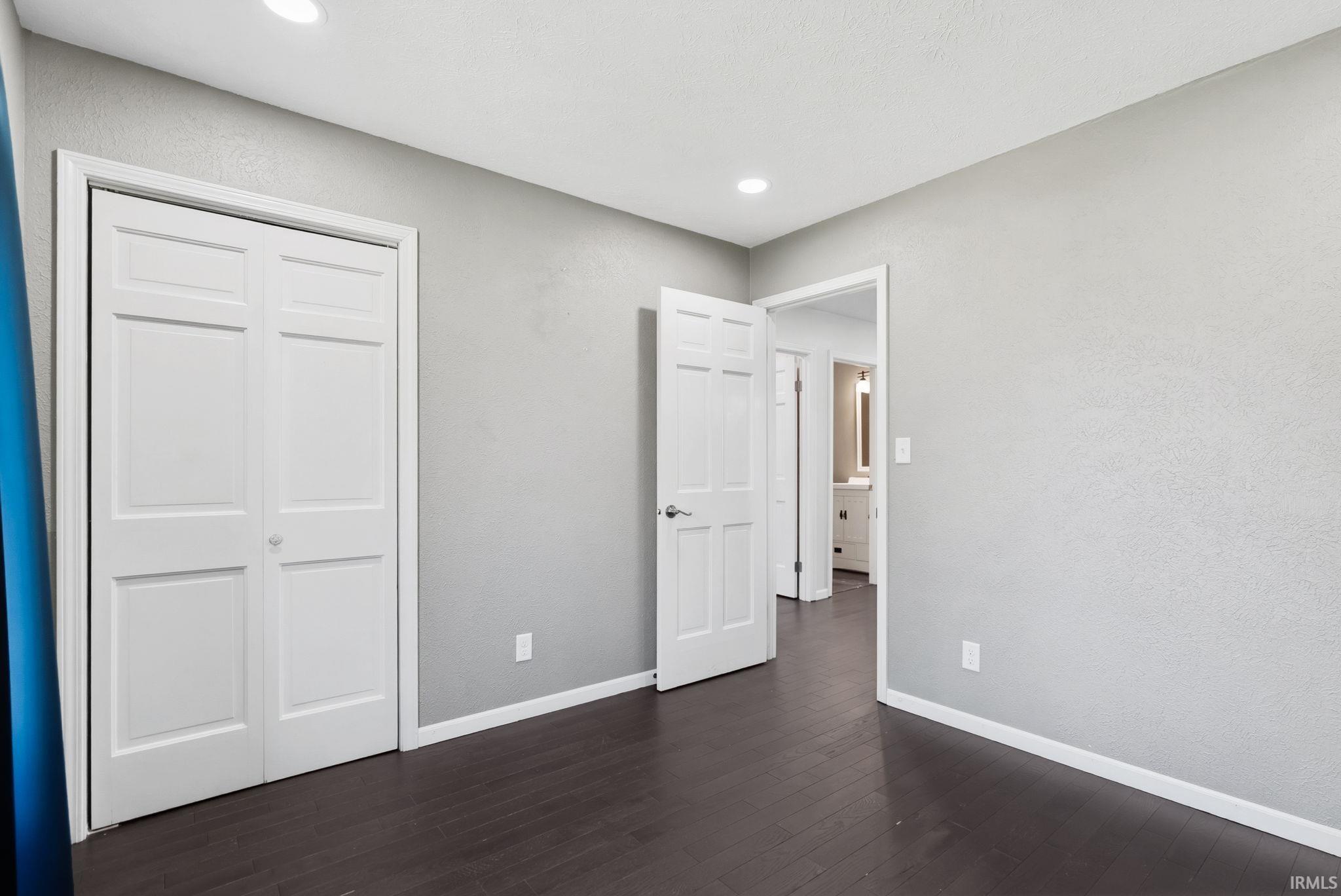 Unfurnished bedroom with dark wood-style floors and a closet