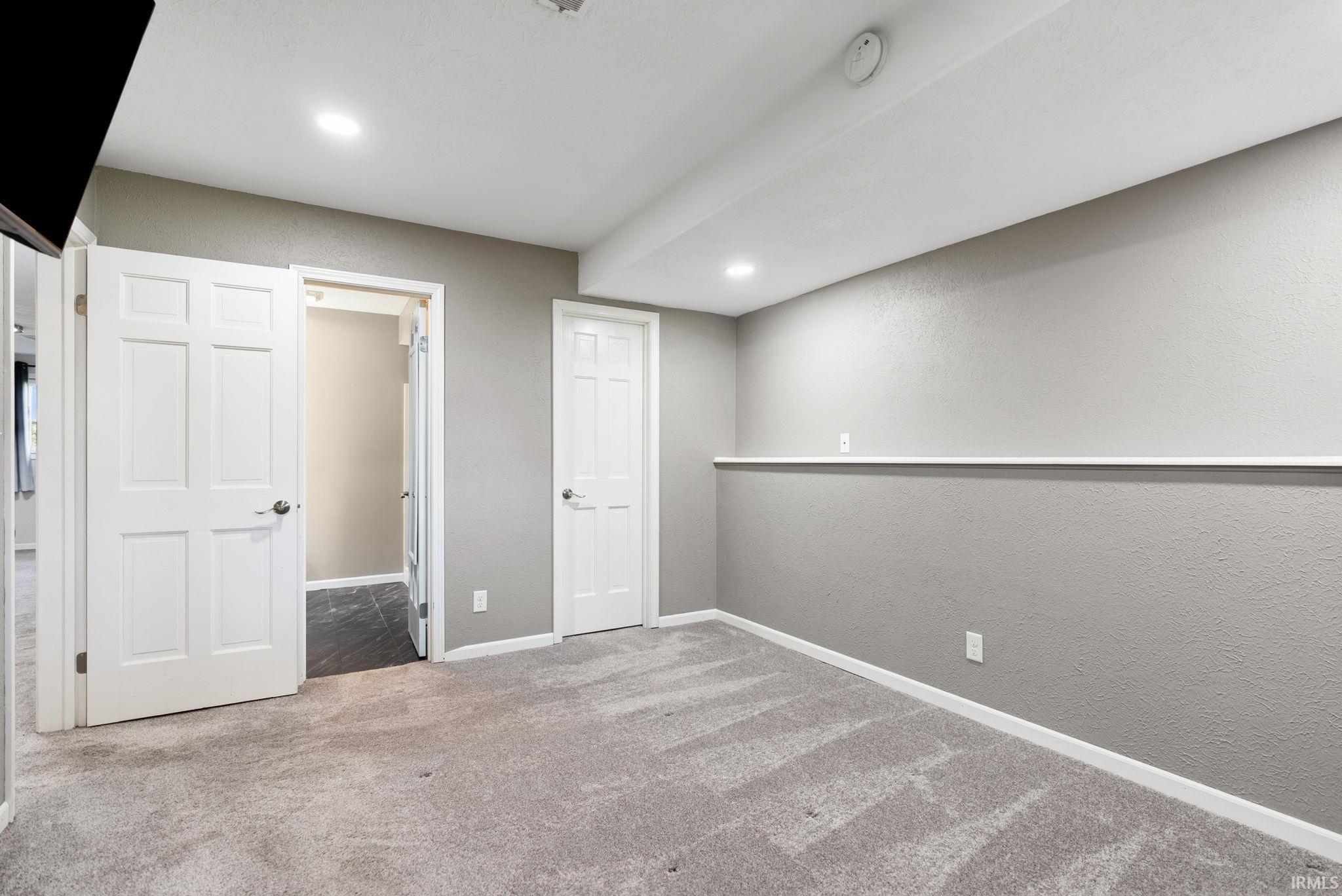 Unfurnished bedroom featuring a textured wall, light colored carpet, and recessed lighting