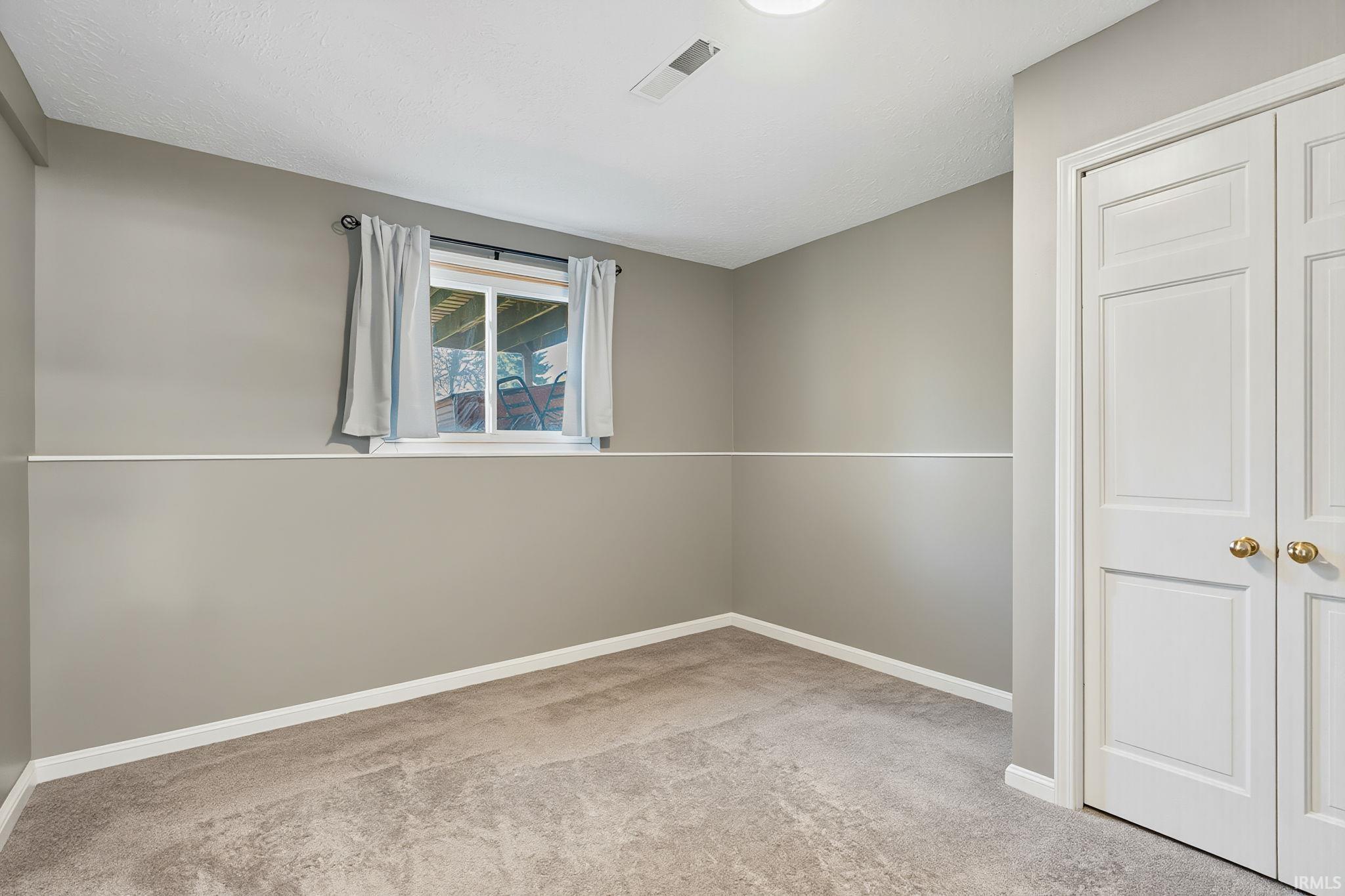 Unfurnished room featuring light carpet and baseboards
