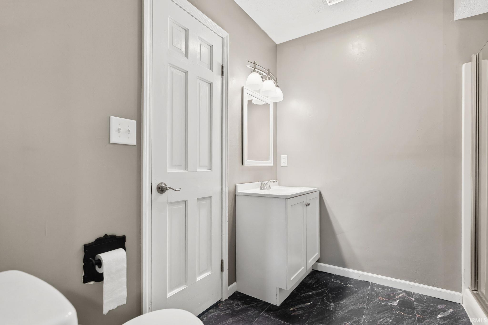 Full bath featuring vanity, a shower stall, and dark marble finish floors