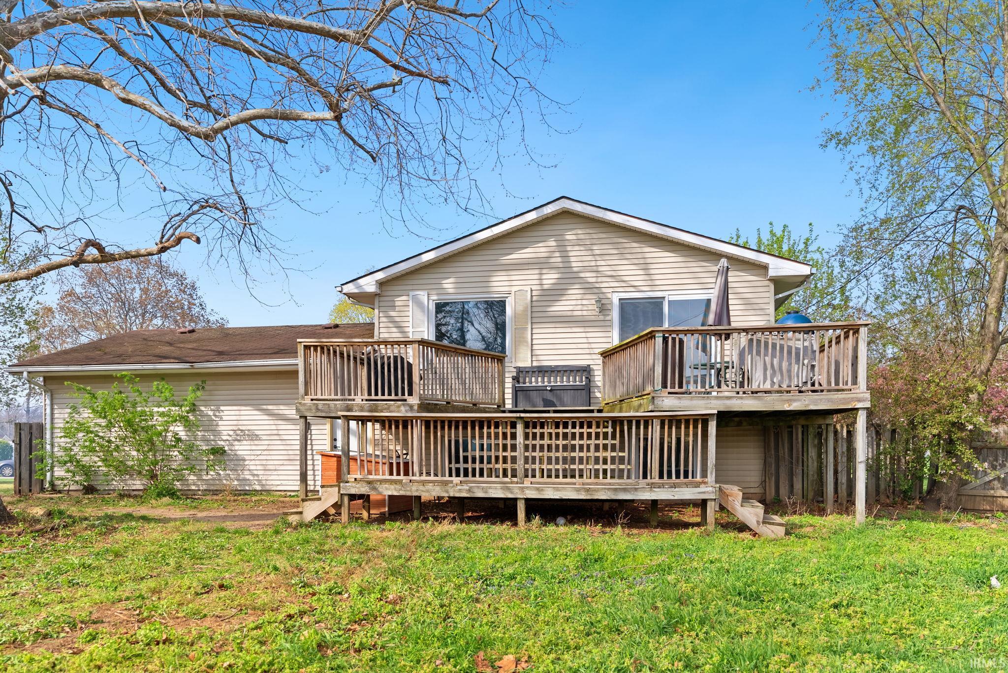 Rear view of house featuring a lawn and a wooden deck