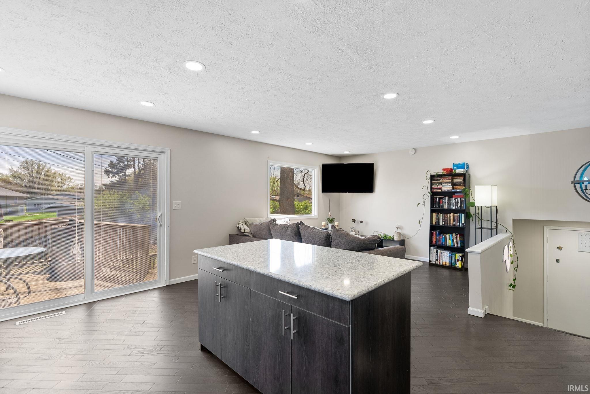 Kitchen featuring a center island, dark wood-type flooring, a textured ceiling, recessed lighting, and open floor plan