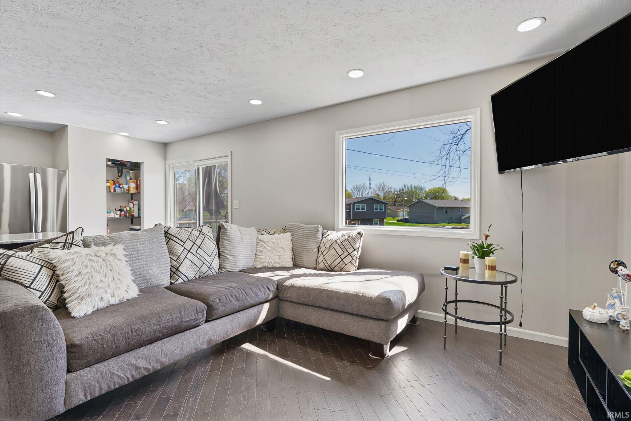 Living room featuring plenty of natural light, recessed lighting, dark wood finished floors, and a textured ceiling