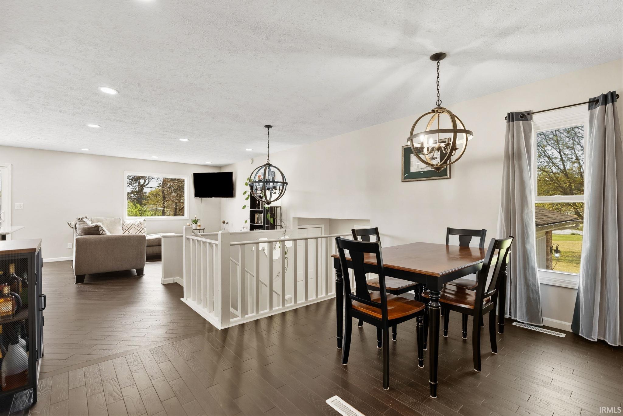 Dining area with suspended lighting, a textured ceiling, and dark wood finished floors