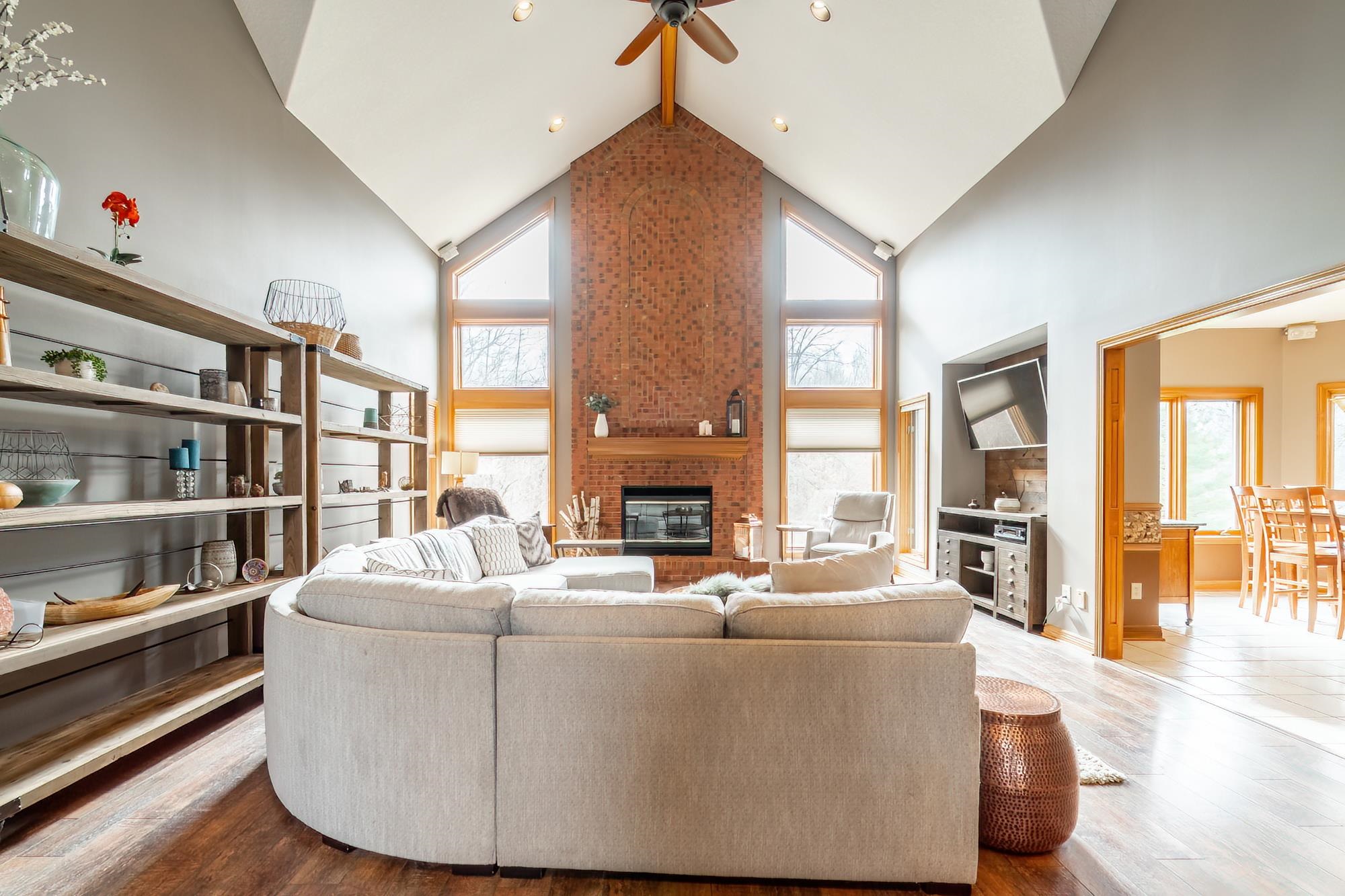 Living area with wood finished floors, ceiling fan, and a brick fireplace