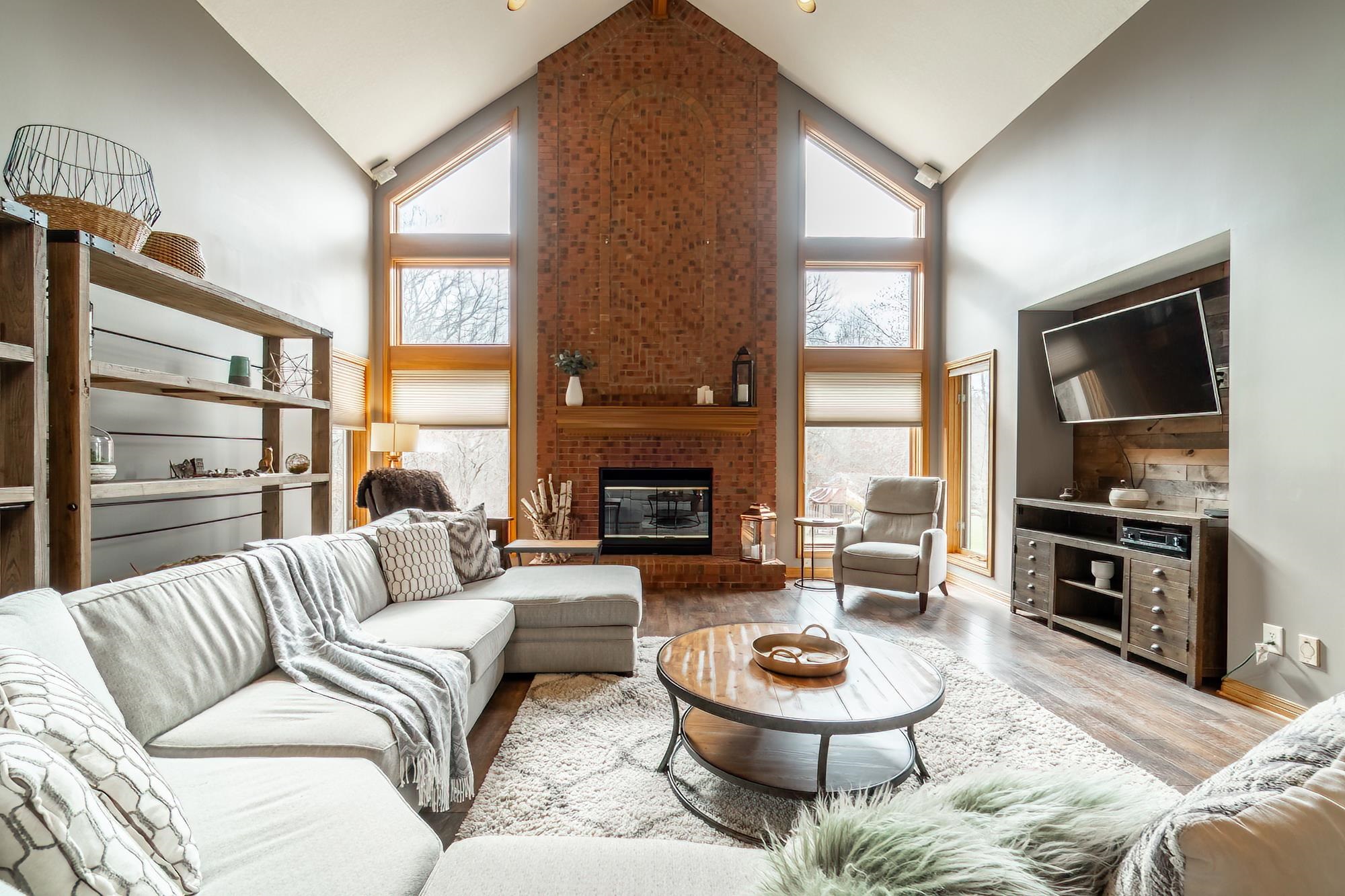 Living room with wood finished floors, a high ceiling, and a brick fireplace