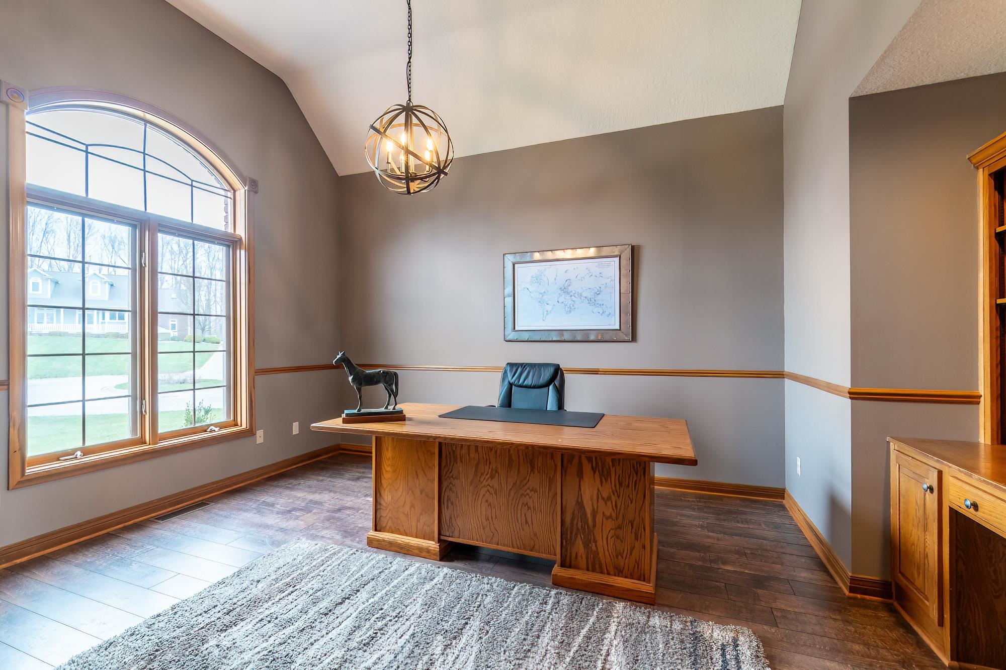 Office space featuring a chandelier, dark wood-type flooring, and vaulted ceiling