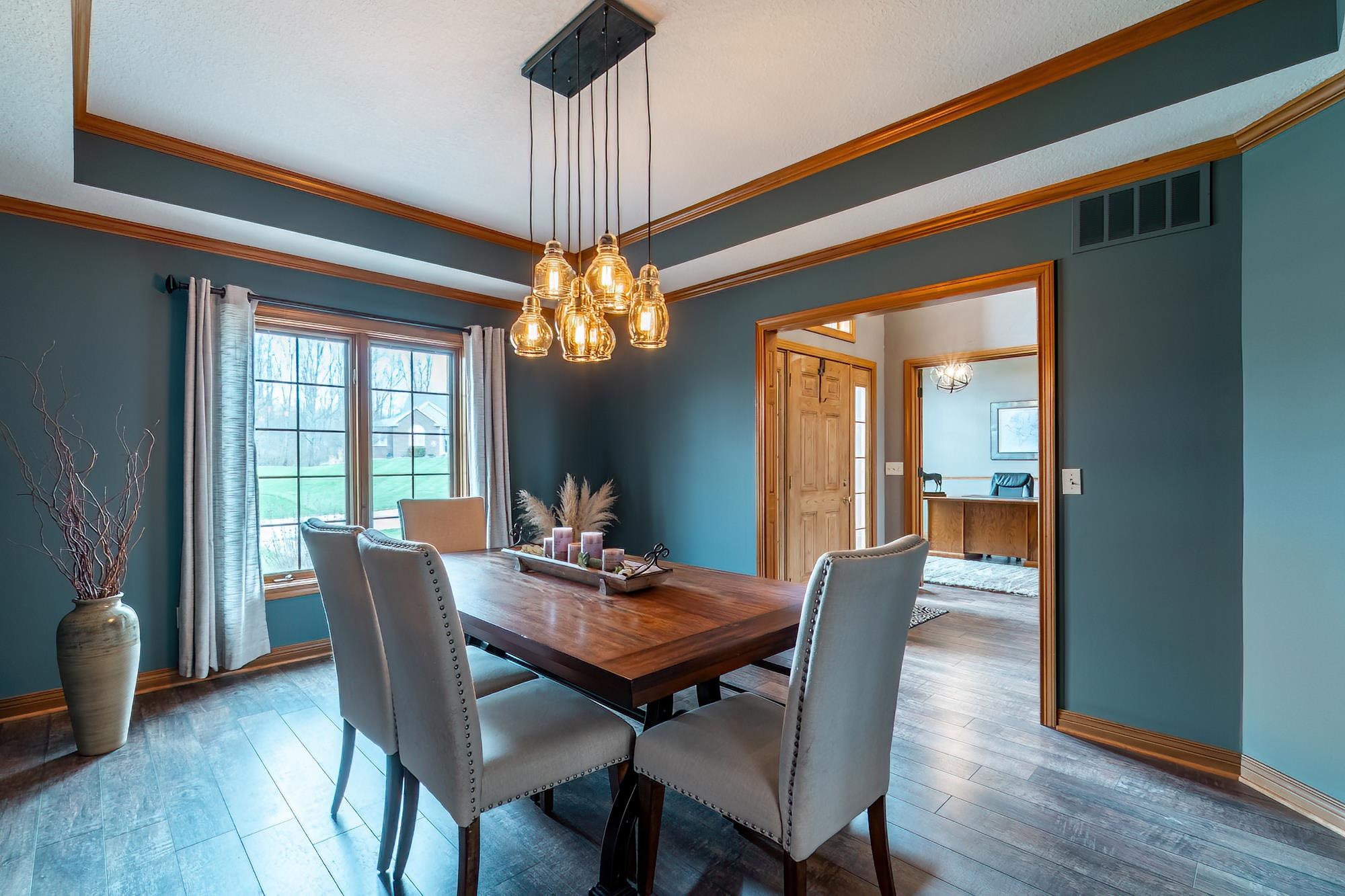 Dining space with hardwood / wood-style flooring, a chandelier, ornamental molding, and a raised ceiling