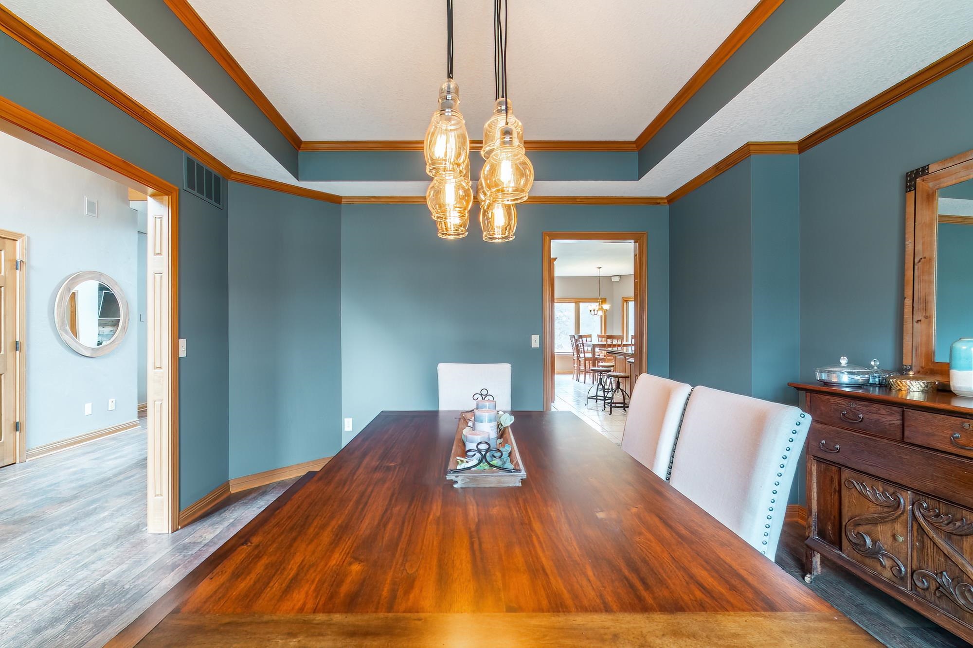 Dining space featuring wood finished floors, crown molding, a raised ceiling, and hanging lights