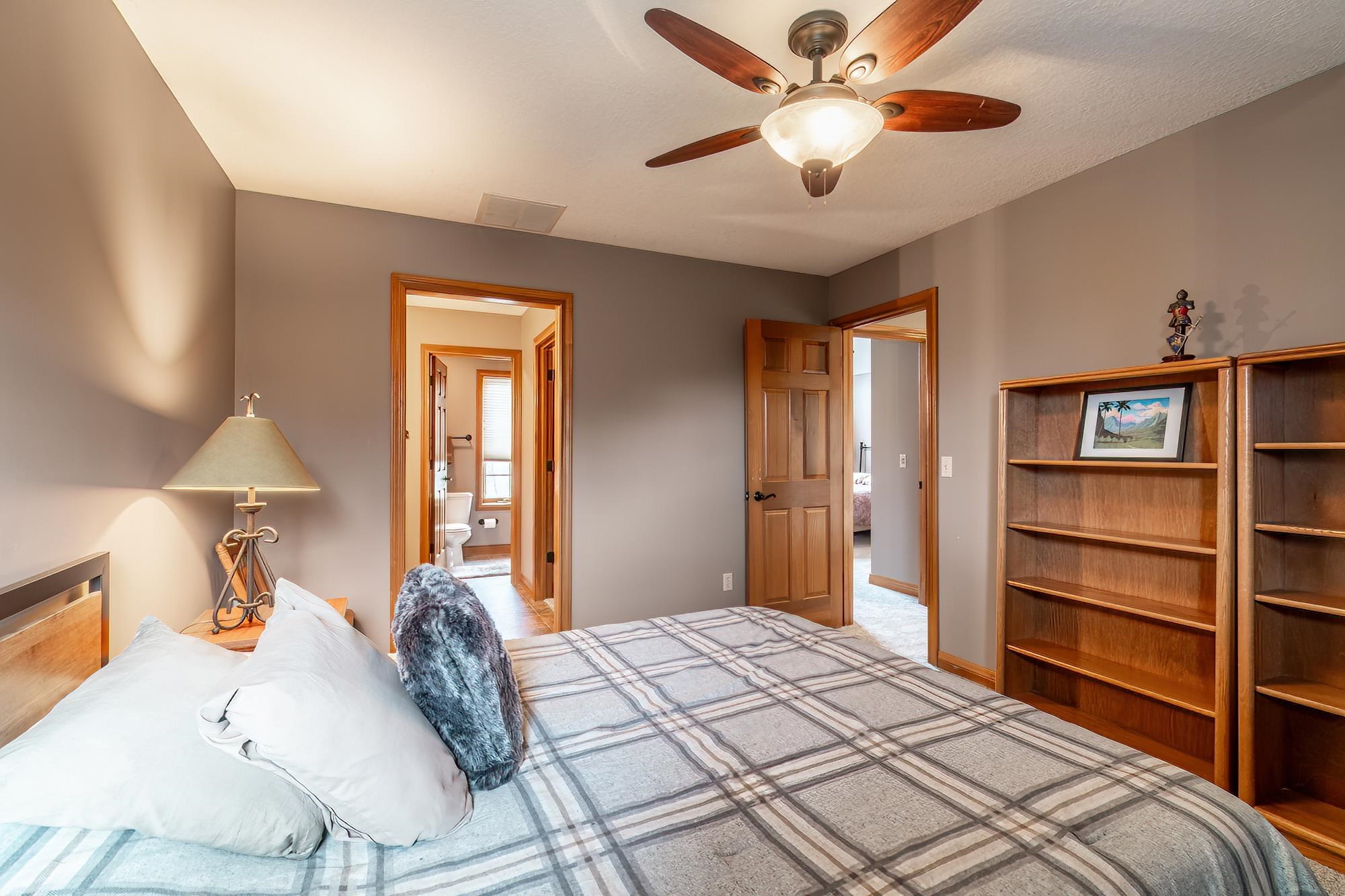 Bedroom with ensuite bath, ceiling fan, and light carpet