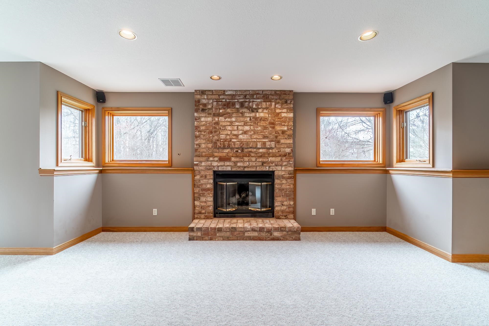 Unfurnished living room featuring a brick fireplace, carpet flooring, and recessed lighting