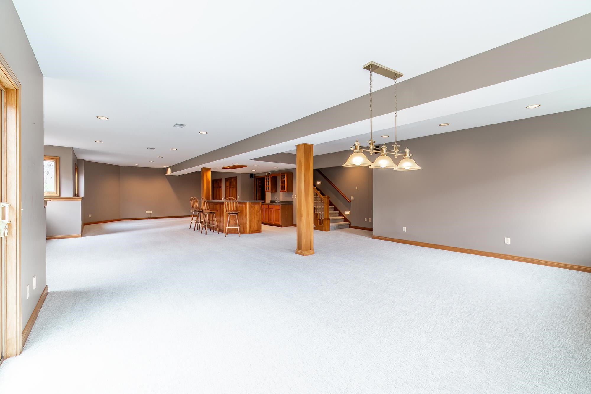 Unfurnished living room featuring a bar, light carpet, and recessed lighting