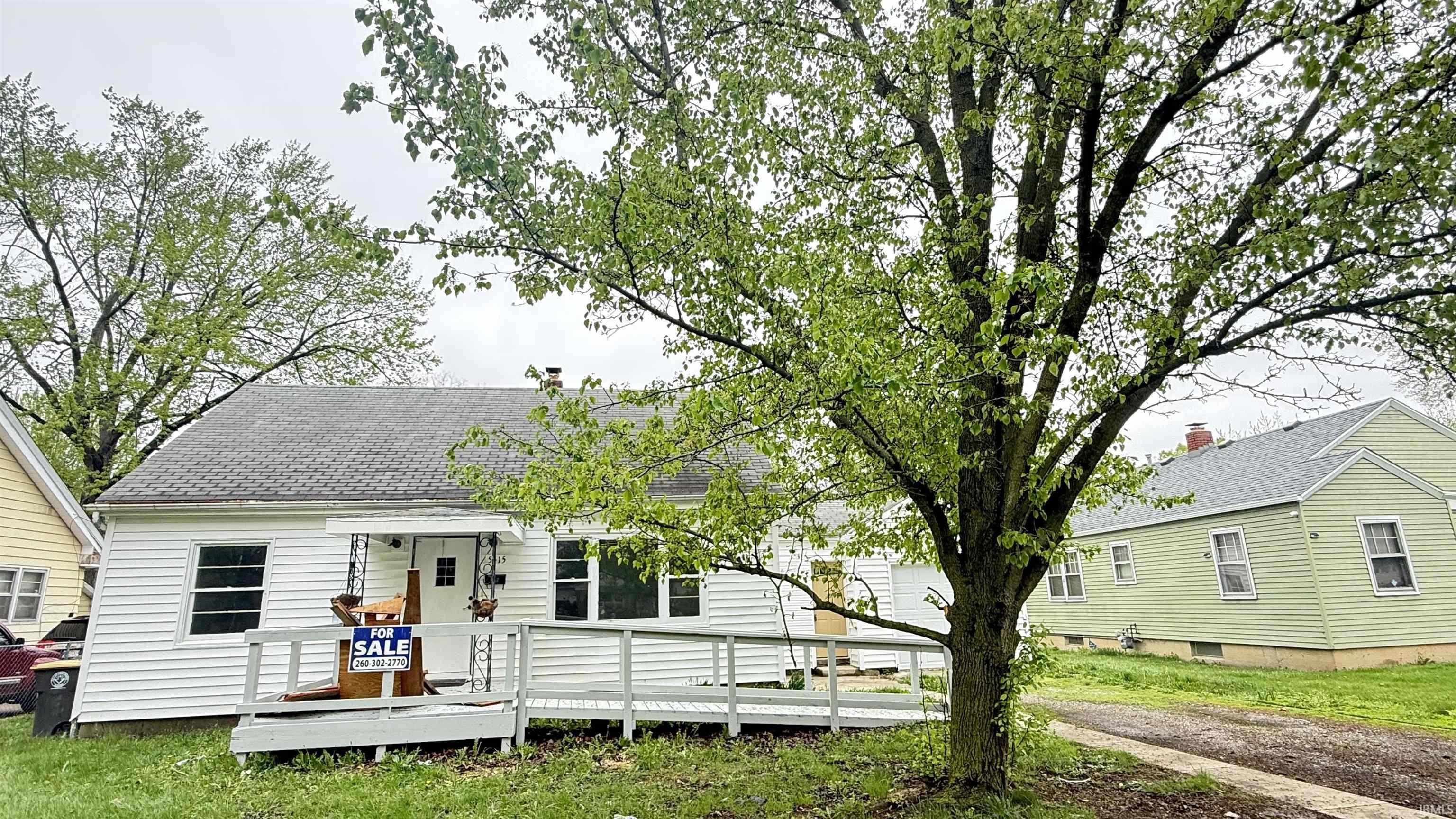 Back of house featuring a shingled roof, a yard, and a wooden deck