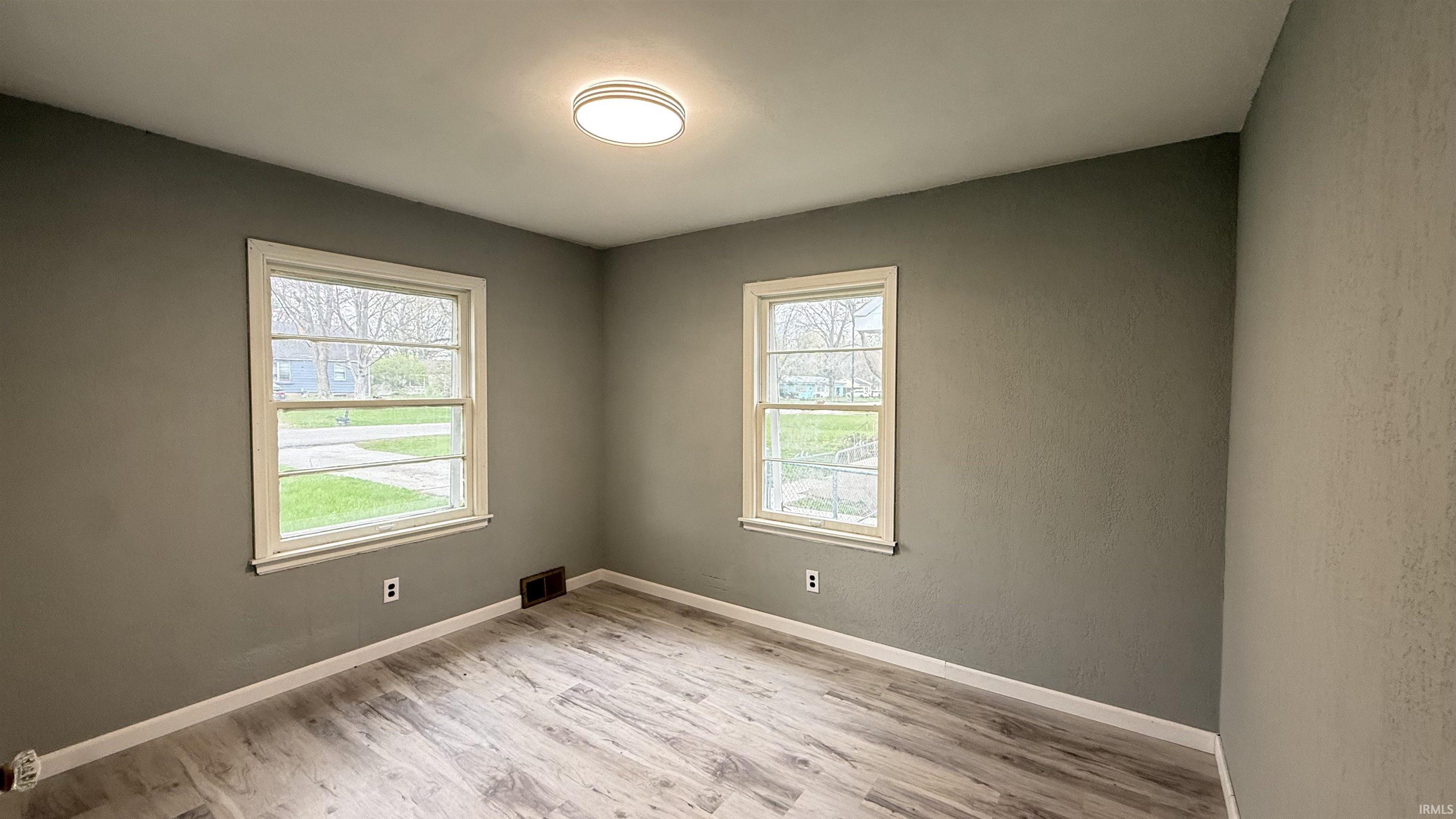 Empty room featuring light wood-style flooring and a textured wall