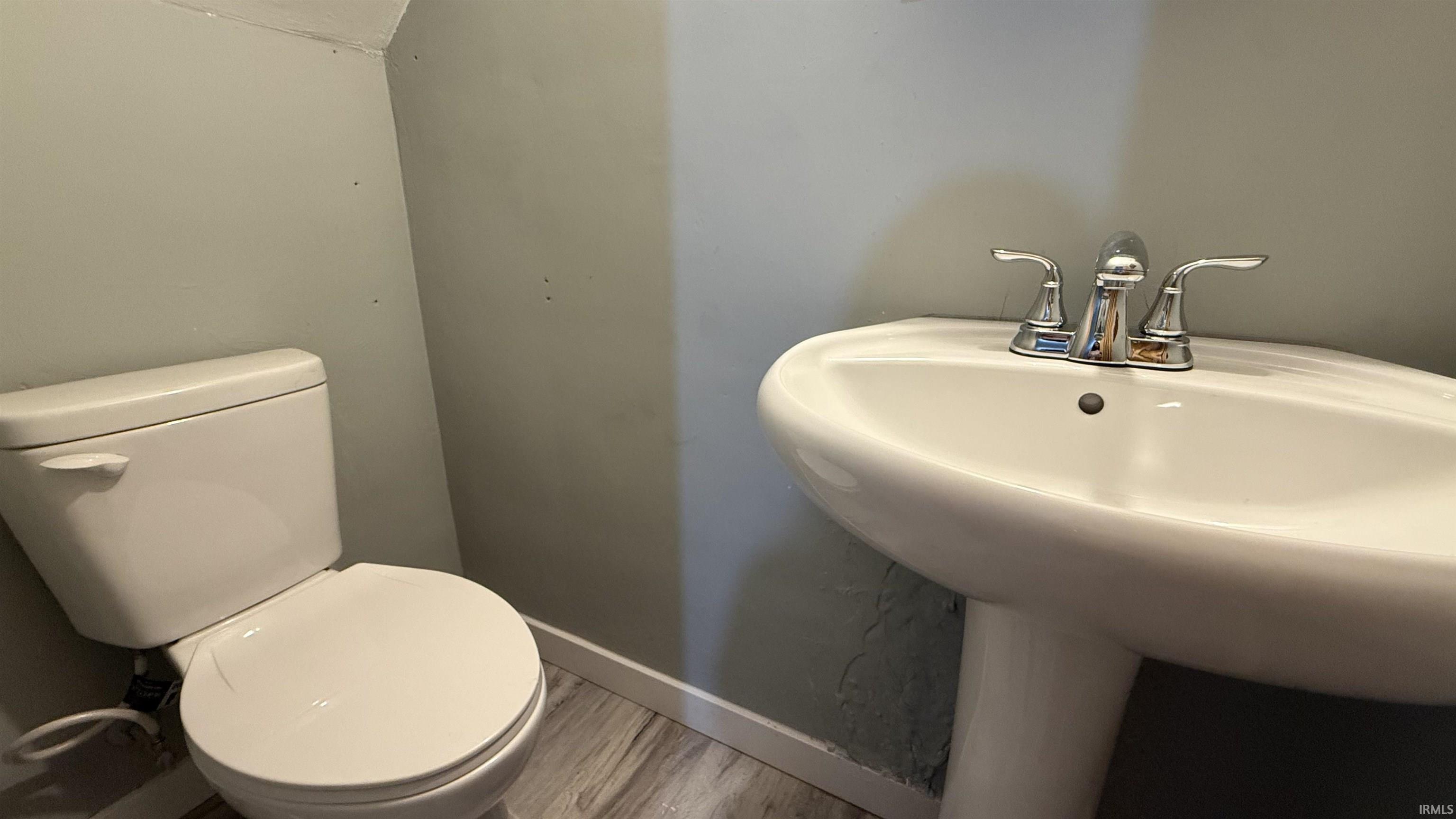 Half bath with toilet and wood finished floors