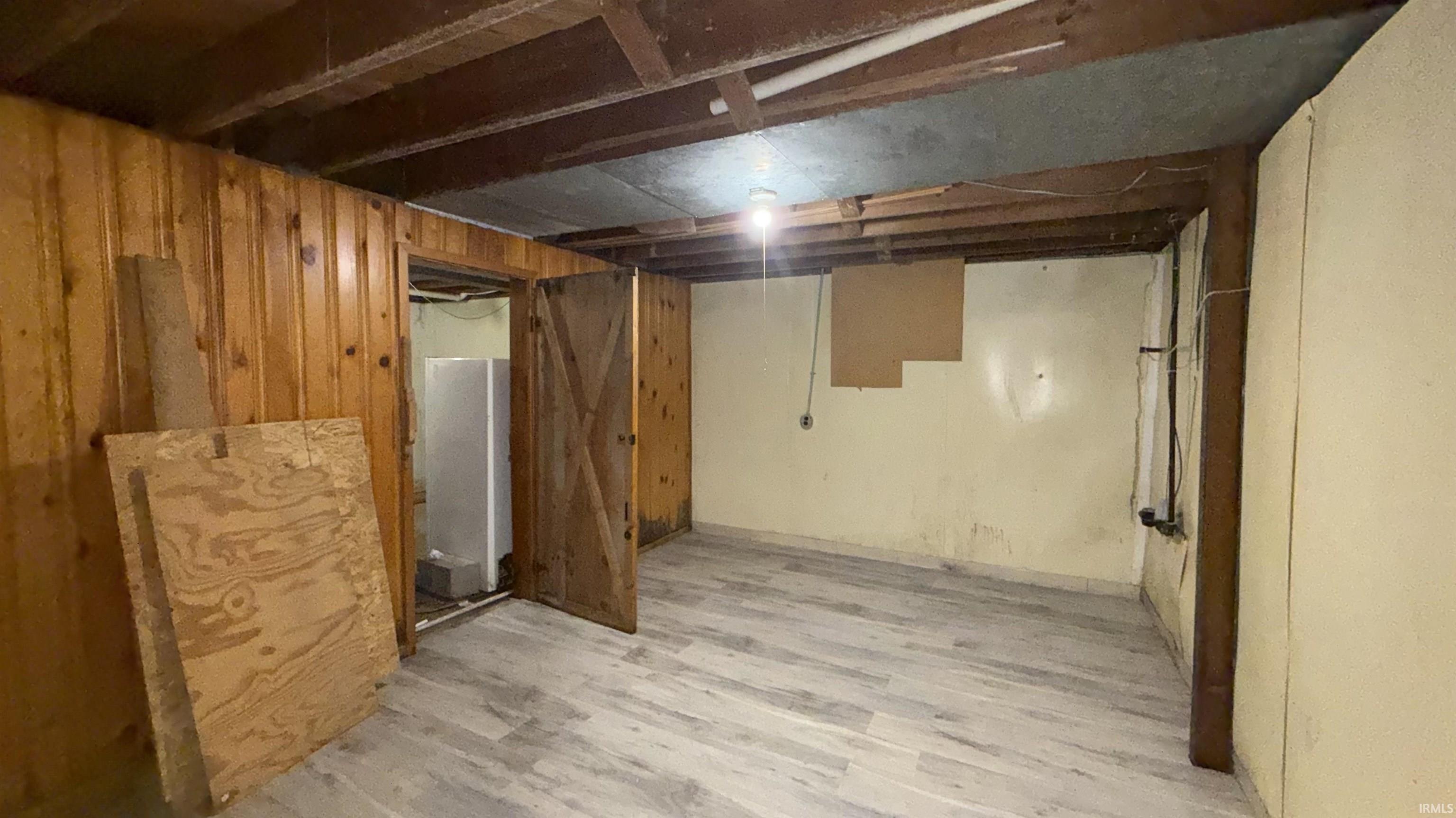 Unfinished below grade area with wooden walls and light wood-type flooring