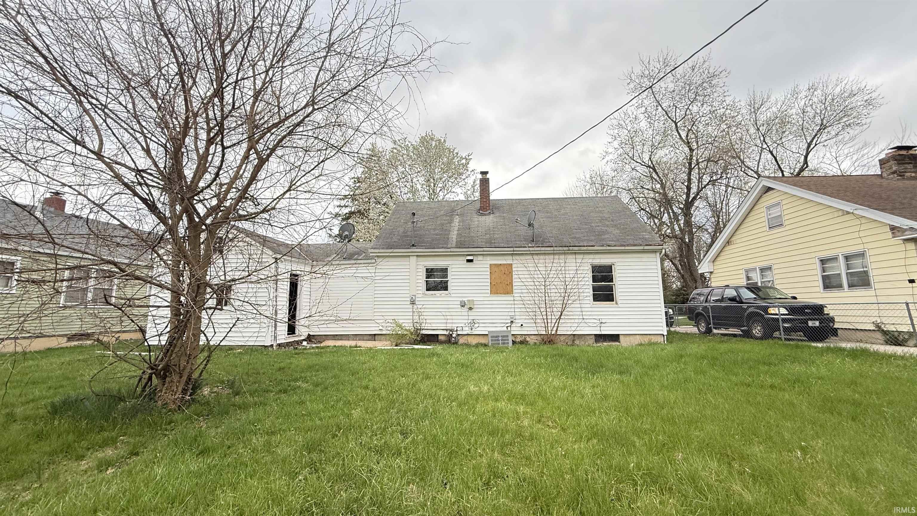 Rear view of house featuring a chimney and a yard