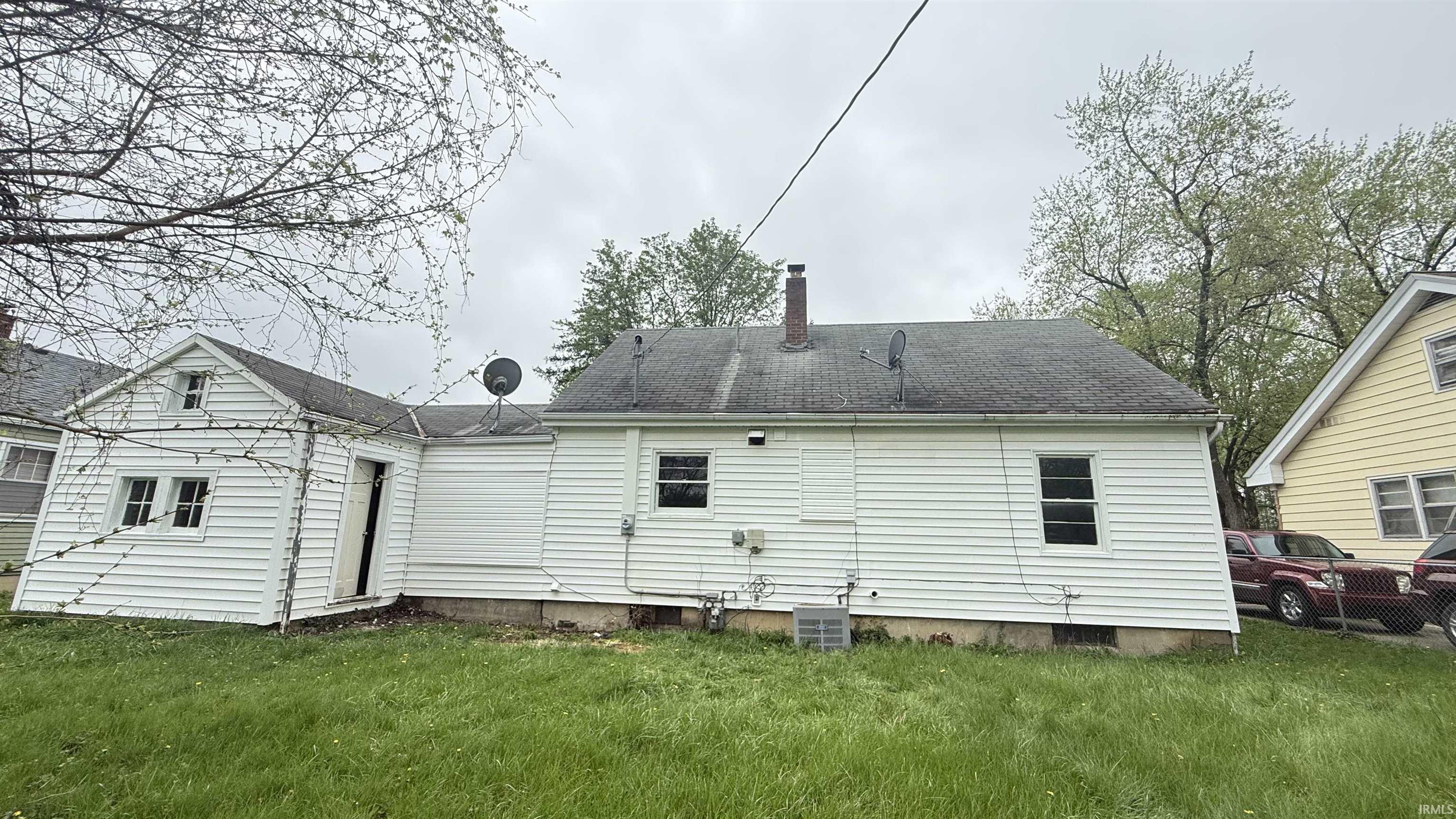 Rear view of property with a lawn, a chimney, and a shingled roof