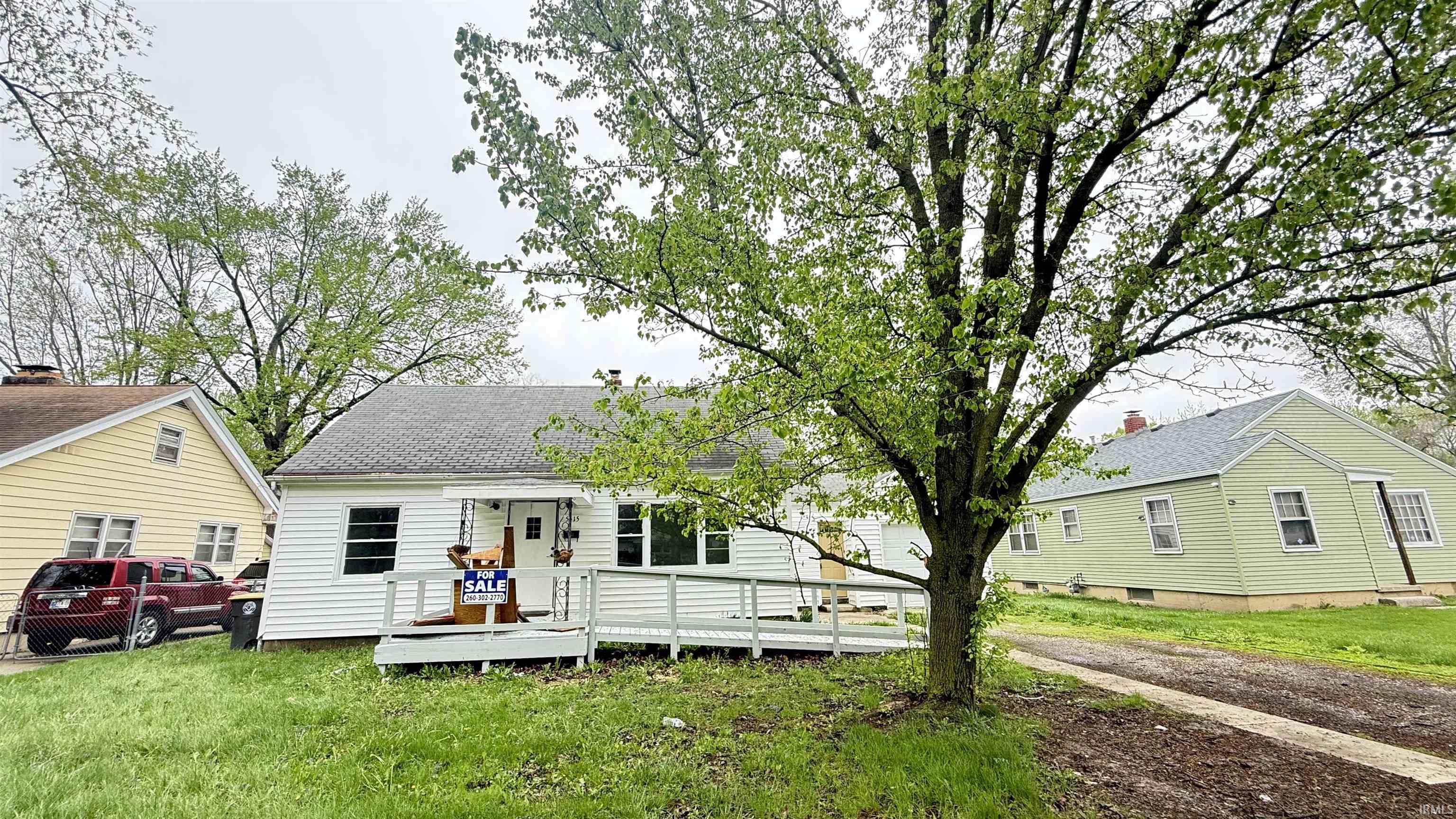 View of front of property featuring a deck, a front yard, and roof with shingles