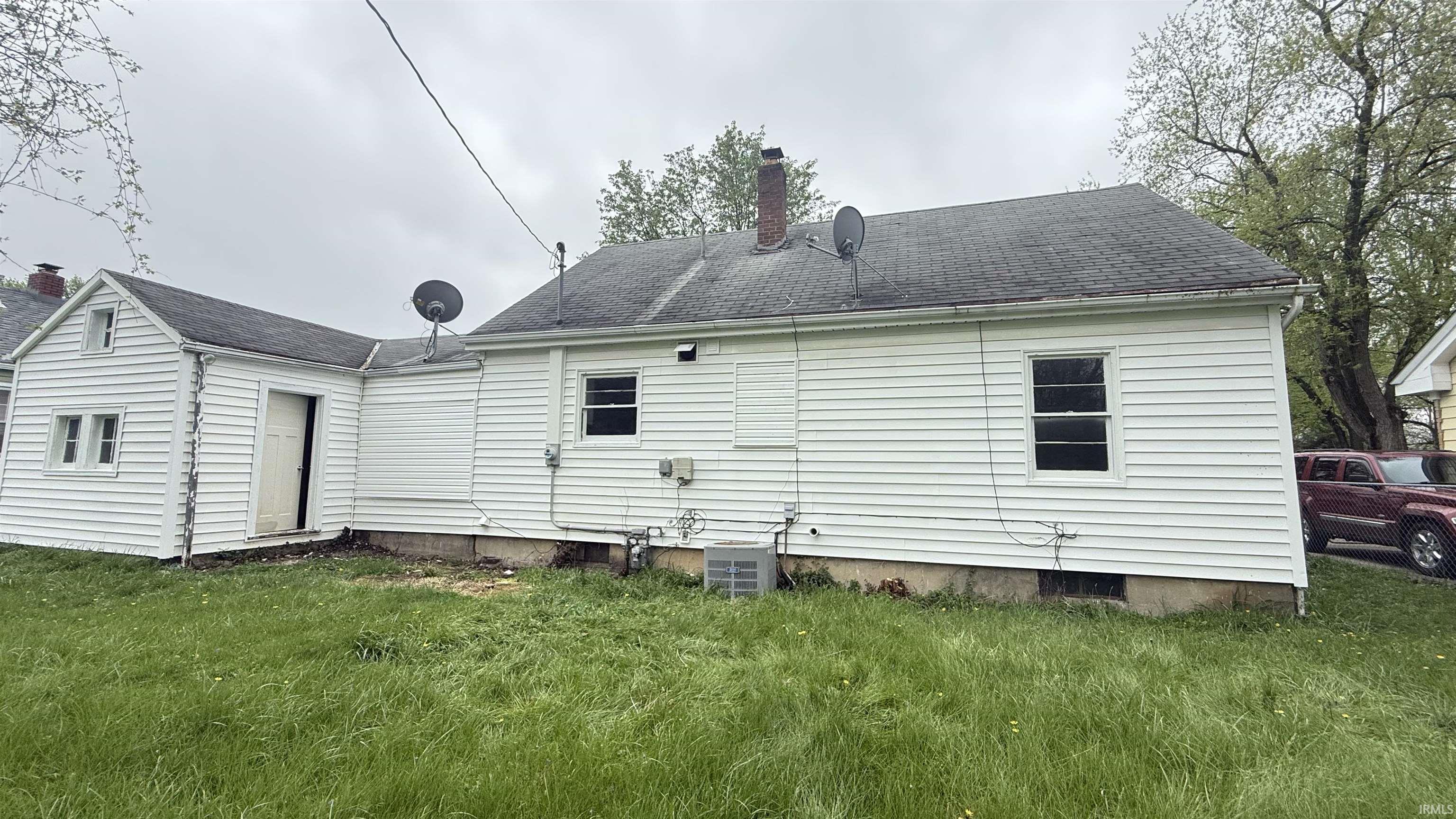 Back of property with a lawn, a chimney, and a shingled roof