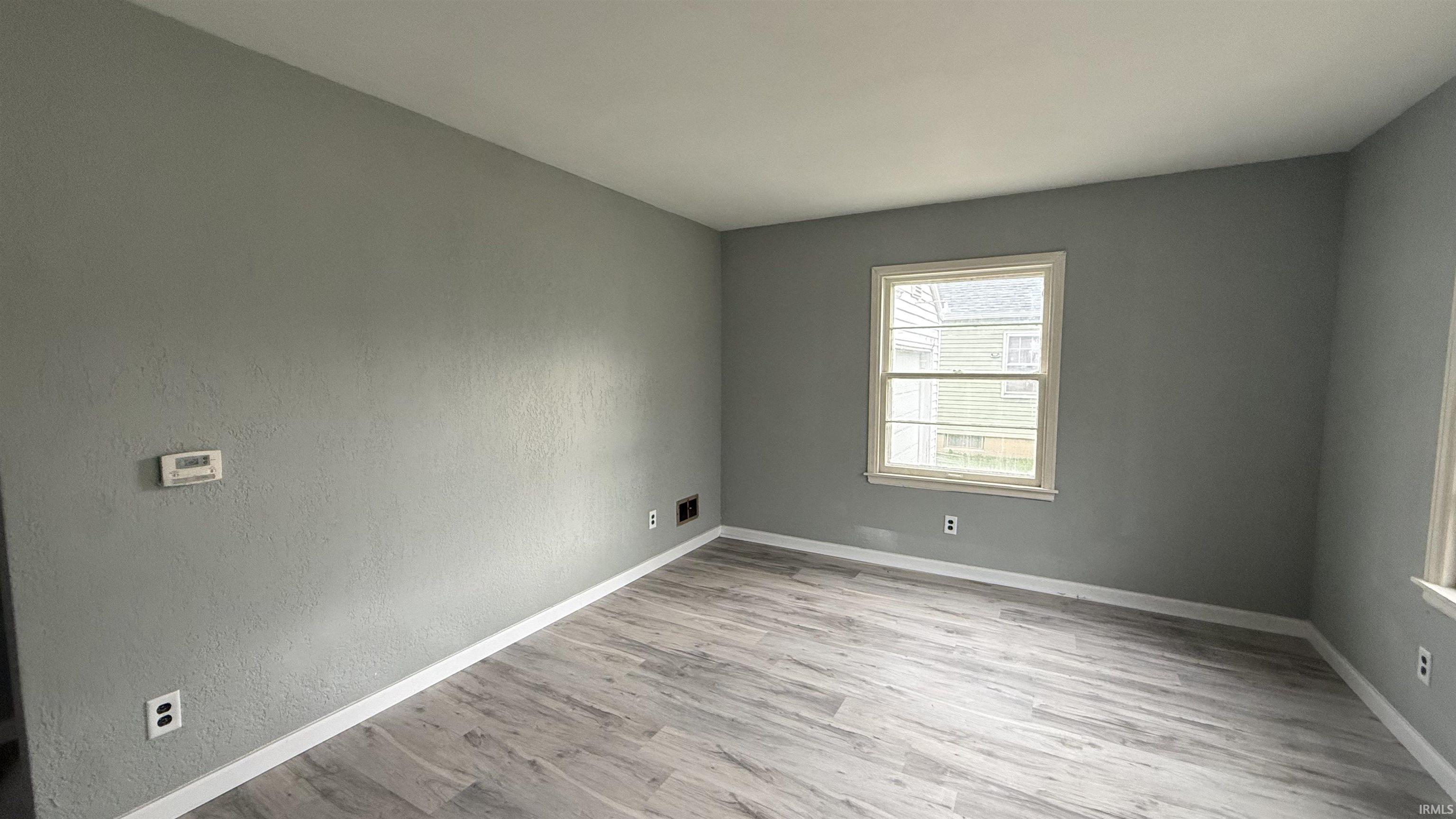 Spare room with baseboards and light wood-type flooring