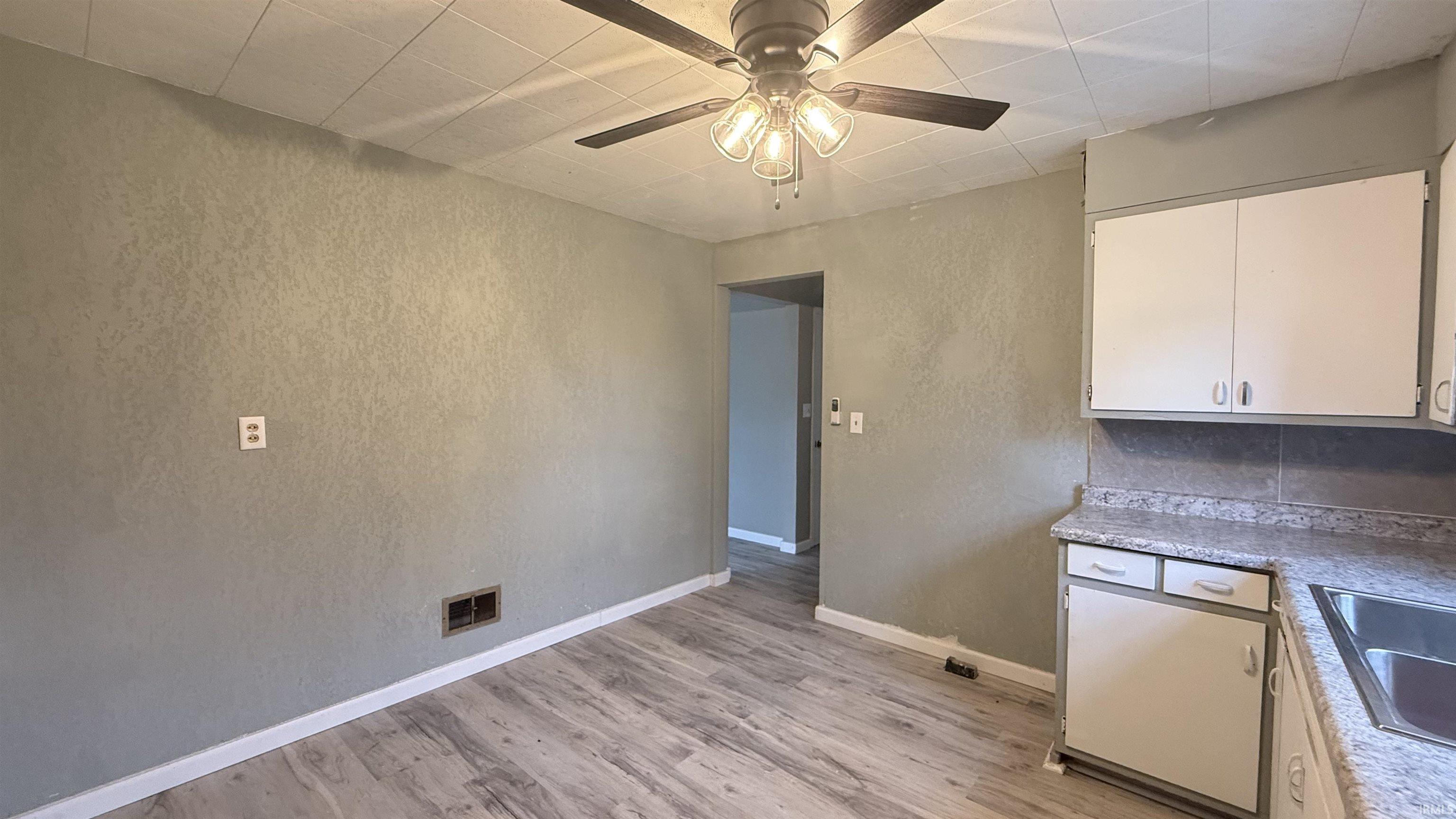 Kitchen with white cabinets, light countertops, light wood-style floors, and a textured wall