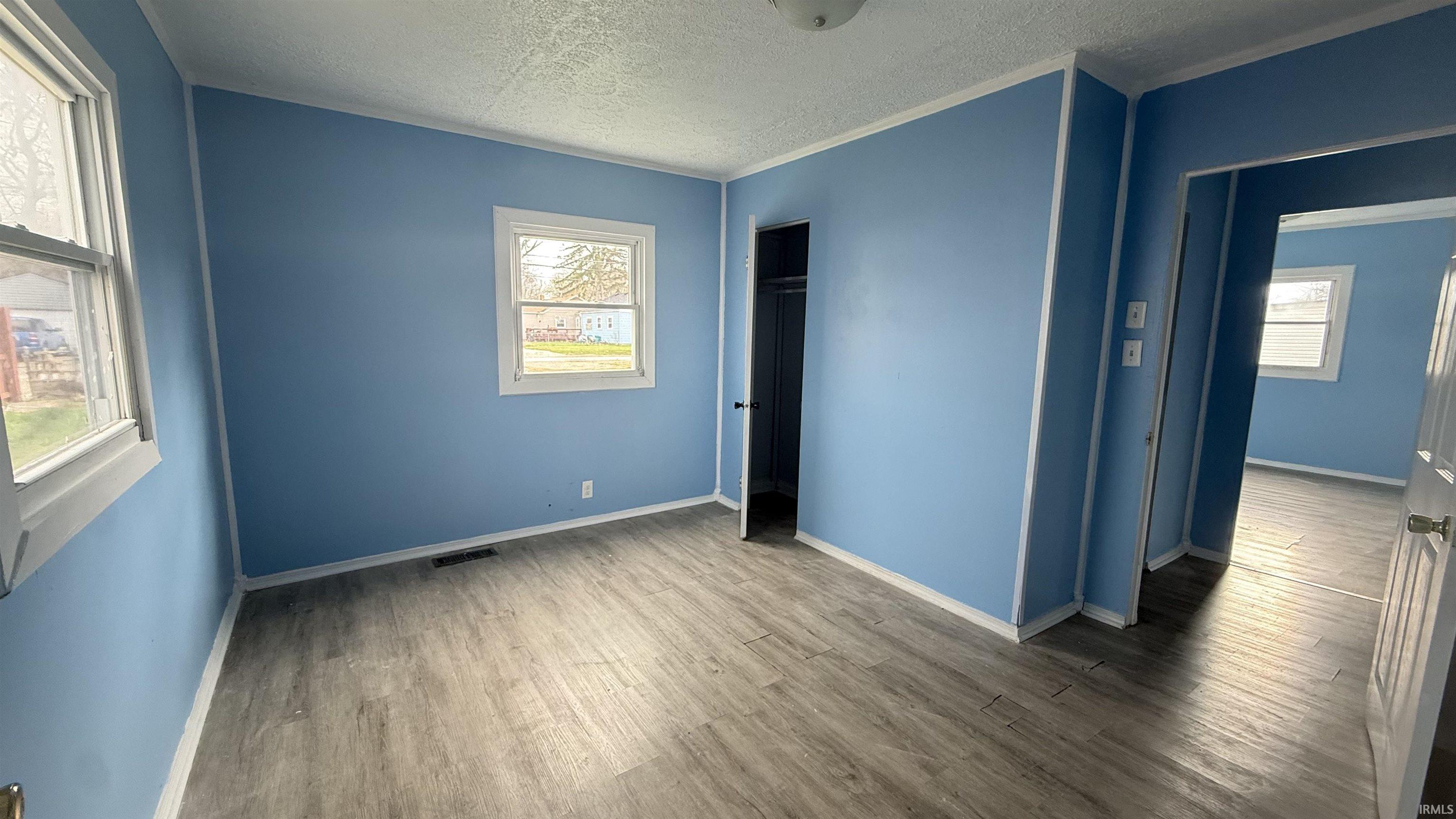 Unfurnished bedroom with light wood finished floors, a textured ceiling, and a closet