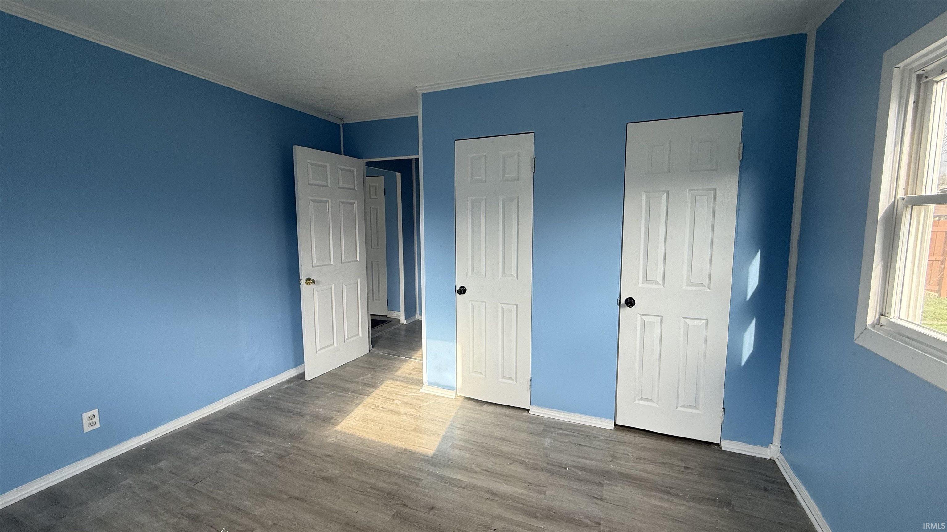 Unfurnished bedroom featuring dark wood-type flooring
